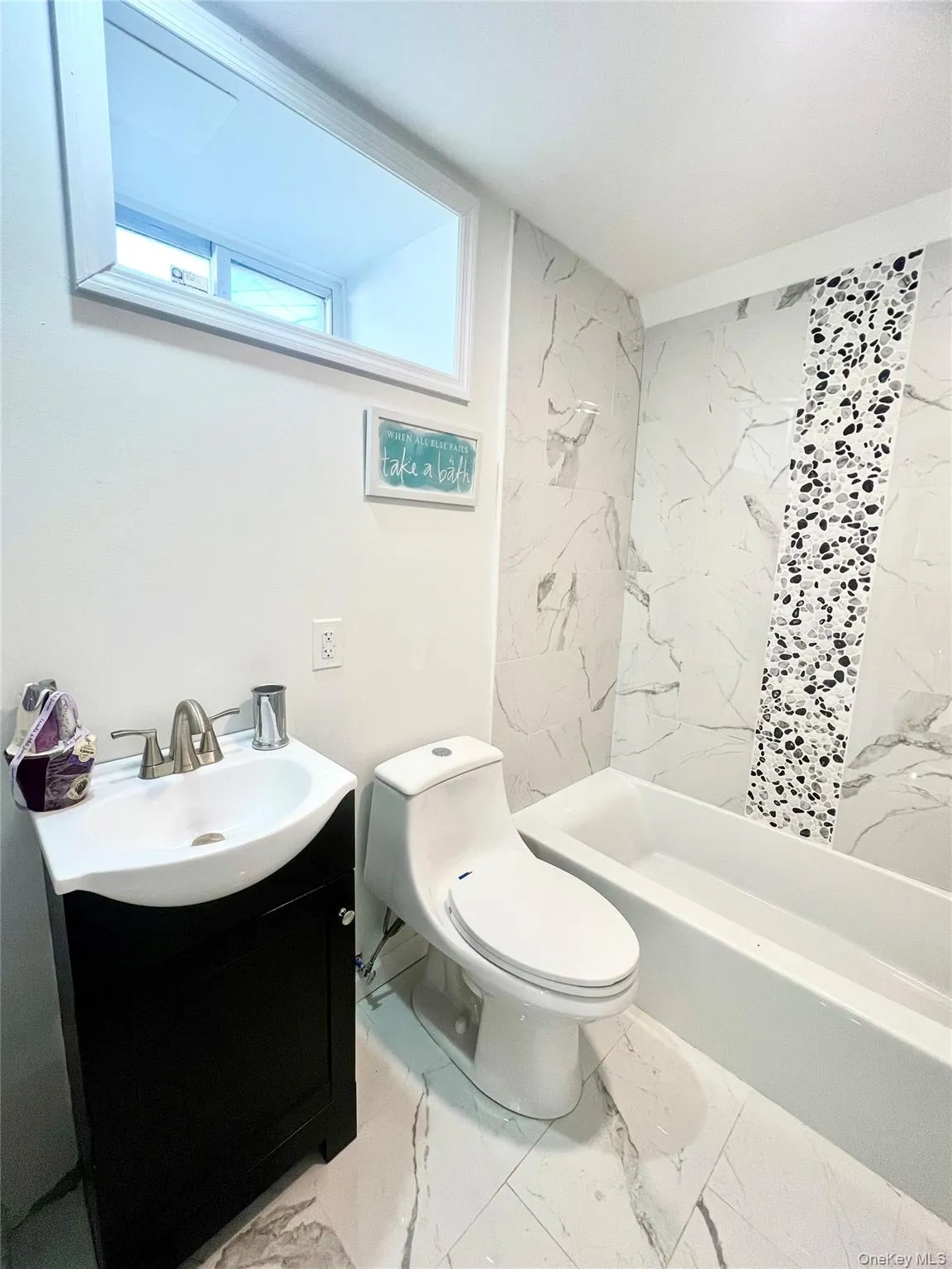 Full bathroom with vanity, light marble finish flooring, and a combined bath / shower with marble appearance Full bathroom with vanity, light marble finish flooring, and a combined bath / shower with marble appearance