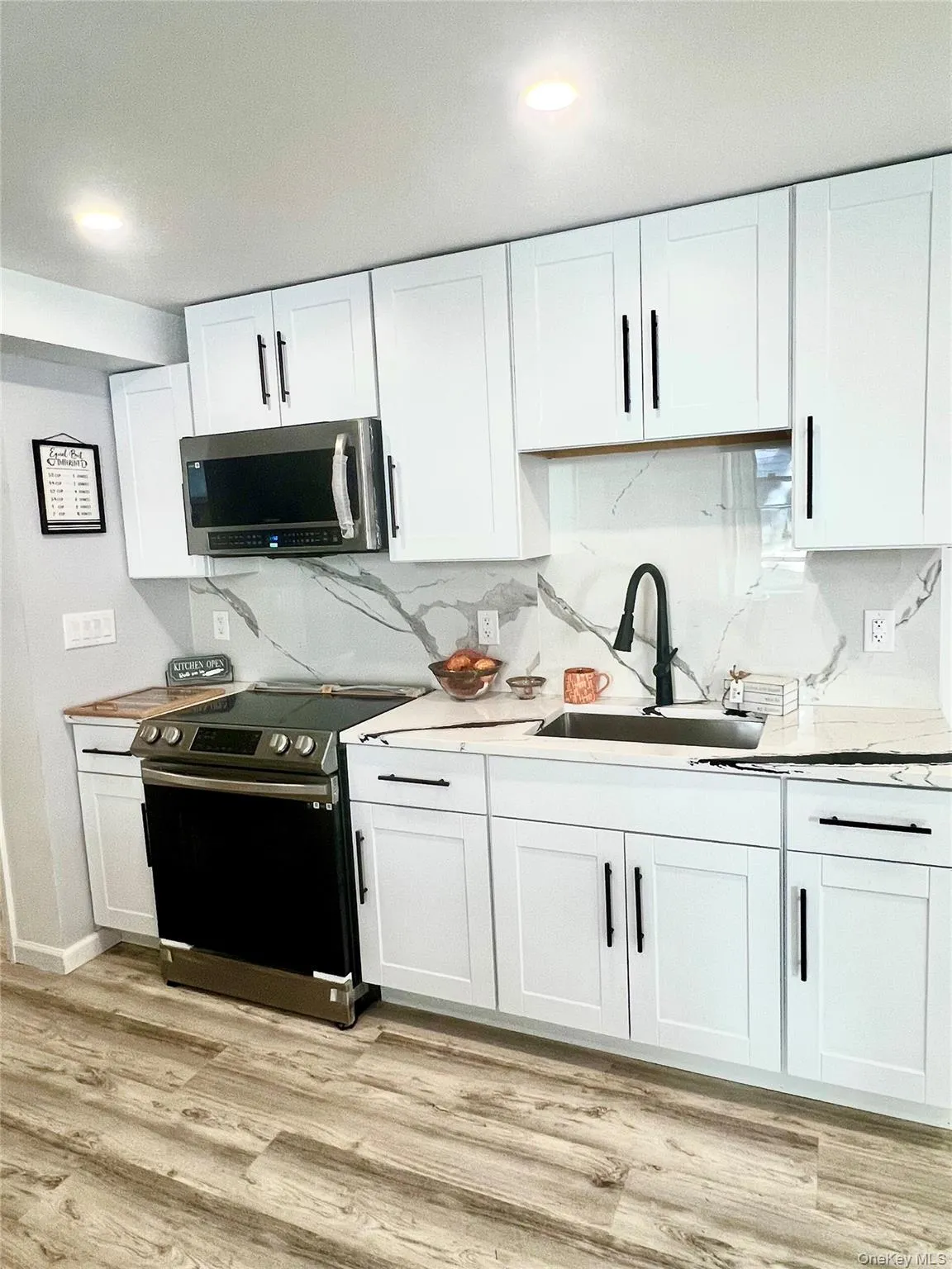 Kitchen with appliances with stainless steel finishes, white cabinetry, light wood-type flooring, and recessed lighting Kitchen with appliances with stainless steel finishes, white cabinetry, light wood-type flooring, and recessed lighting
