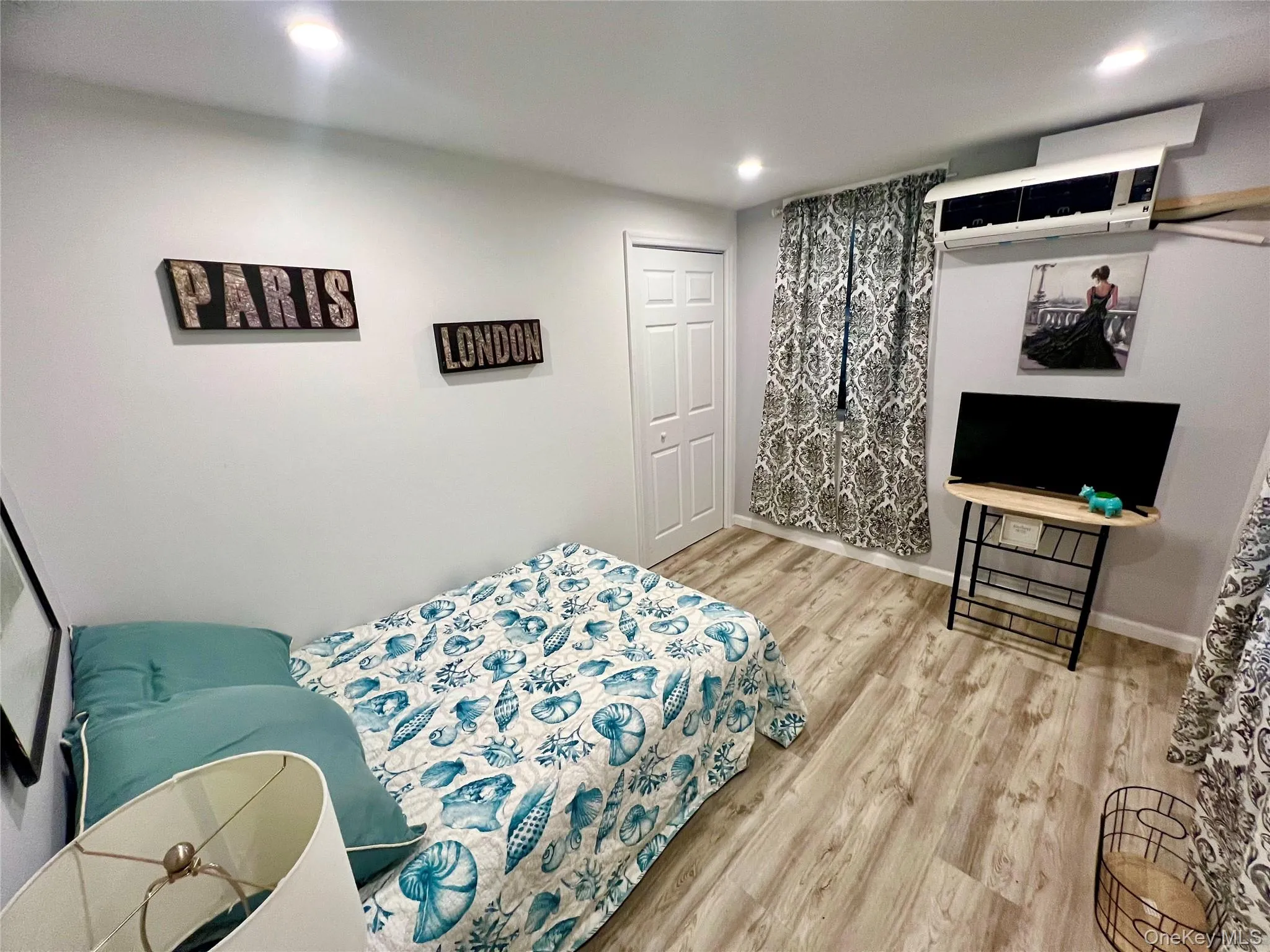 Bedroom with light wood-style flooring, recessed lighting, and an AC wall unit Bedroom with light wood-style flooring, recessed lighting, and an AC wall unit