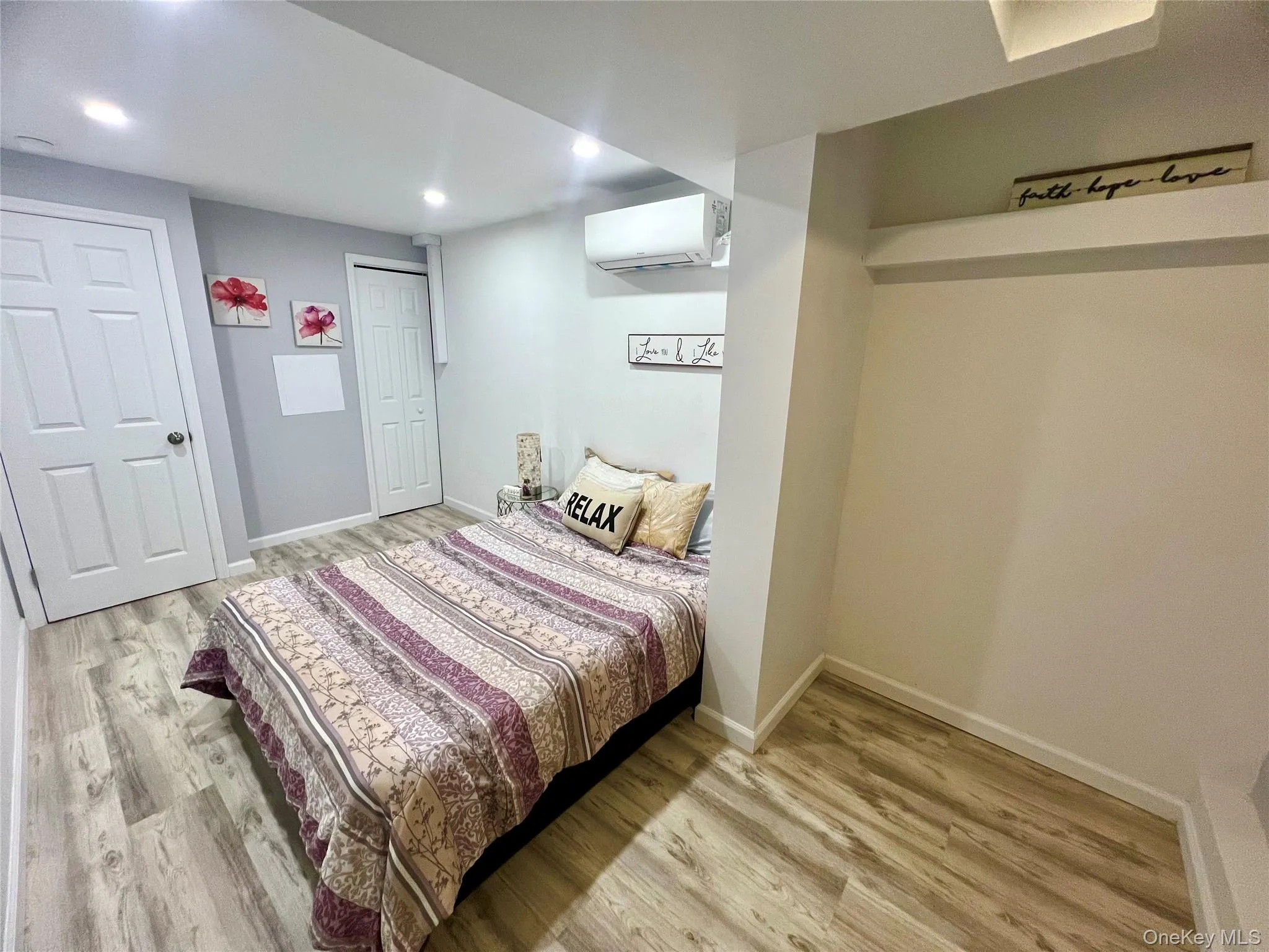 Bedroom with light wood-style floors, a wall mounted AC, and recessed lighting Bedroom with light wood-style floors, a wall mounted AC, and recessed lighting