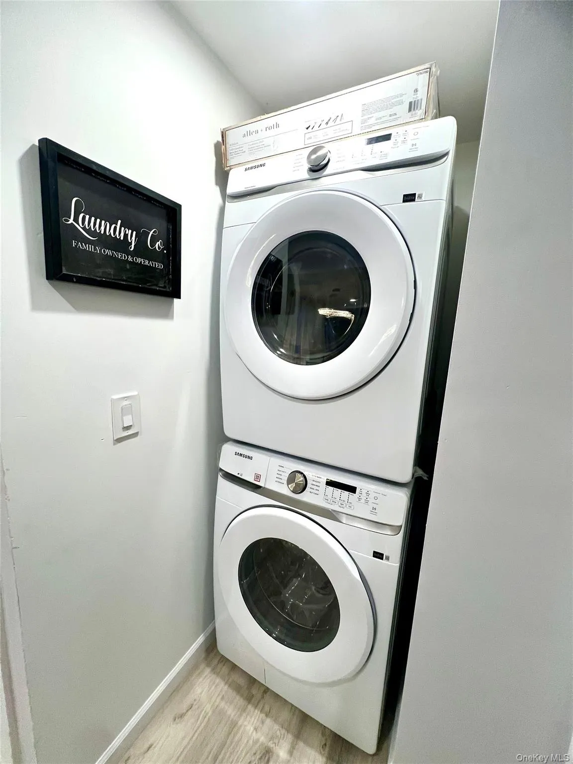Washroom with stacked washer / dryer and light wood finished floors Washroom with stacked washer / dryer and light wood finished floors
