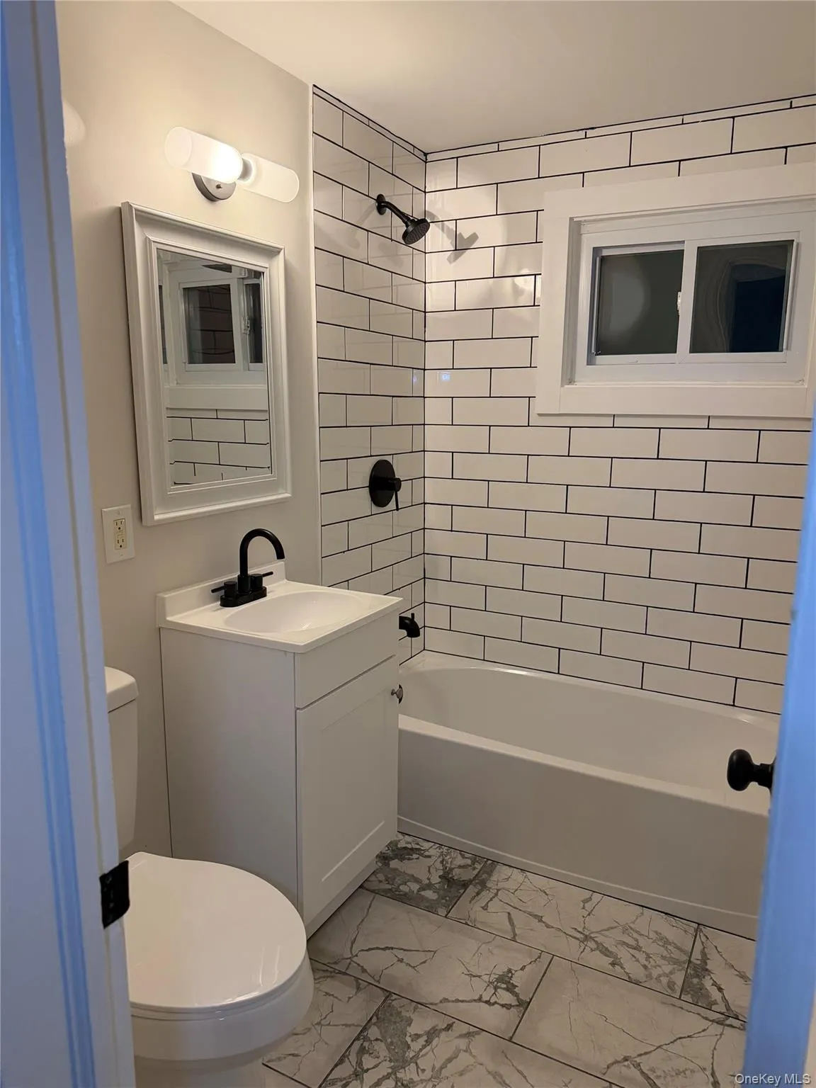 Full bath featuring light marble finish floors, bathing tub / shower combination, and vanity Full bath featuring light marble finish floors, bathing tub / shower combination, and vanity