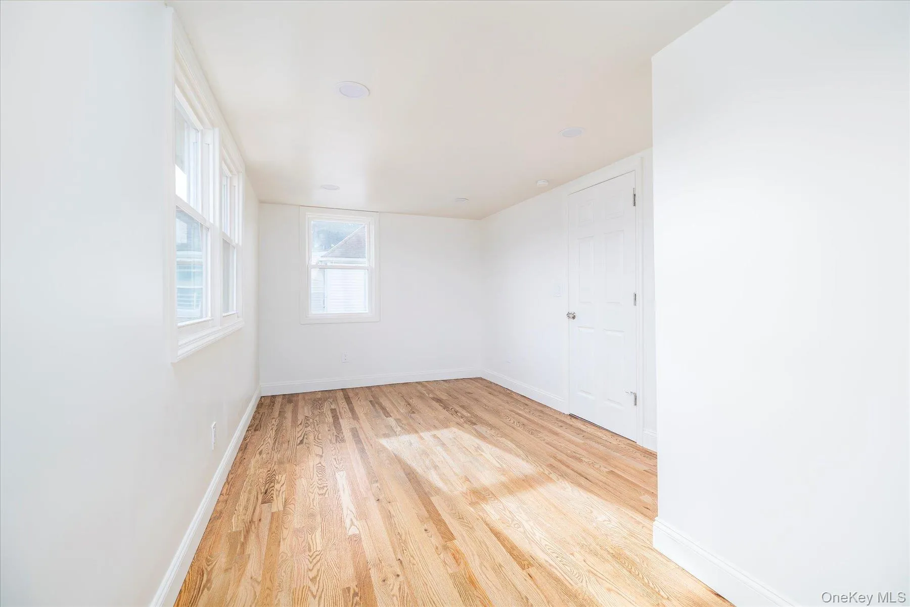 Primary bedroom featuring light wood flooring, plenty of natural light, alcove, 2 closets Primary bedroom featuring light wood flooring, plenty of natural light, alcove, 2 closets