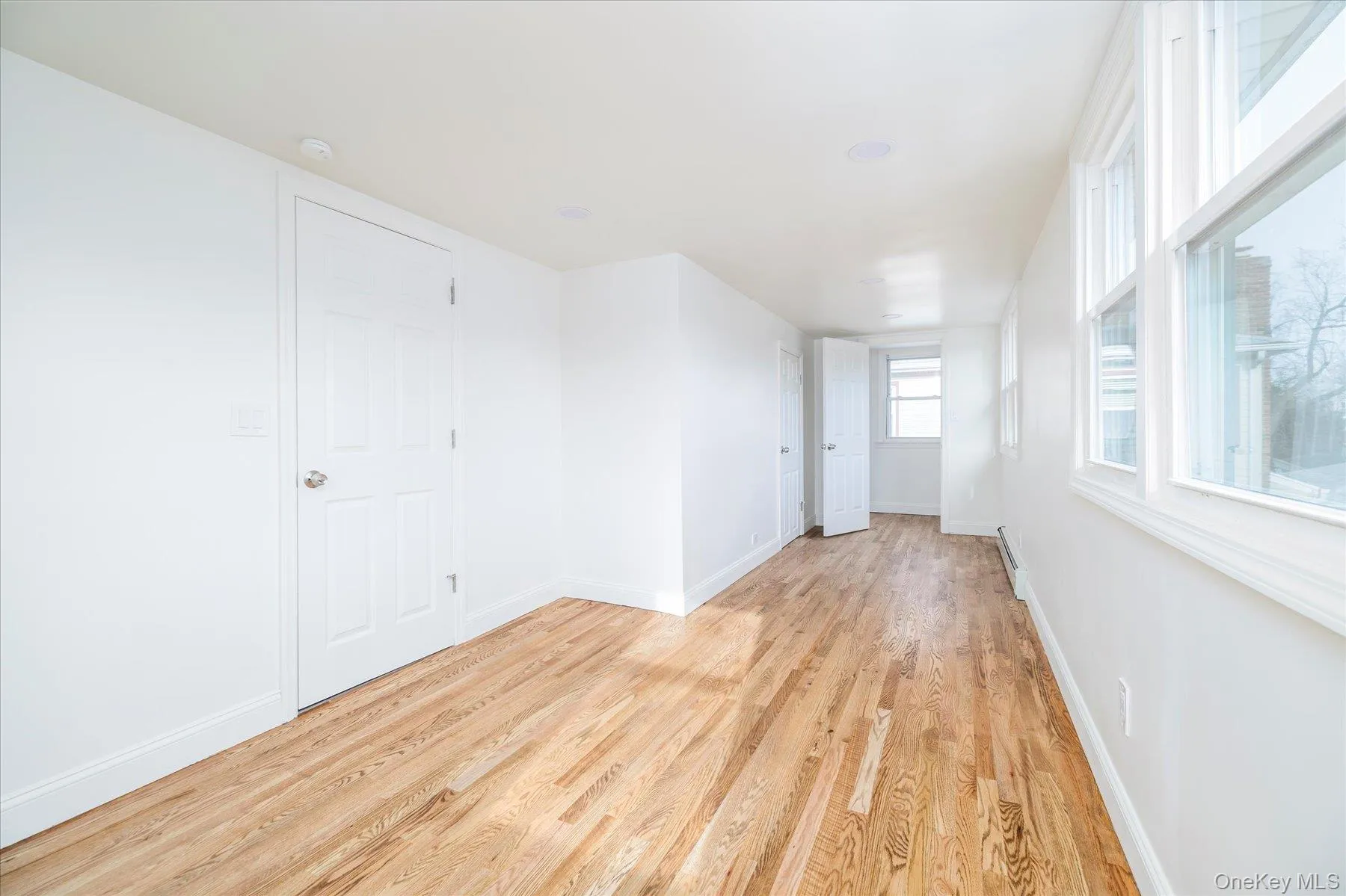 Primary bedroom featuring light wood flooring, plenty of natural light, alcove, 2 closets Primary bedroom featuring light wood flooring, plenty of natural light, alcove, 2 closets