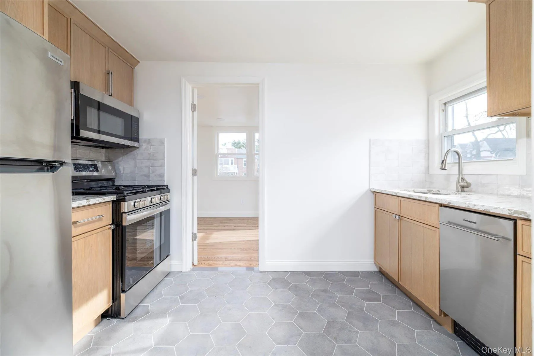 New kitchen featuring white oak cabinets, quartz countertops,ceramic backsplash, stainless steel appliances, & grey tile floor New kitchen featuring white oak cabinets, quartz countertops,ceramic backsplash, stainless steel appliances, & grey tile floor