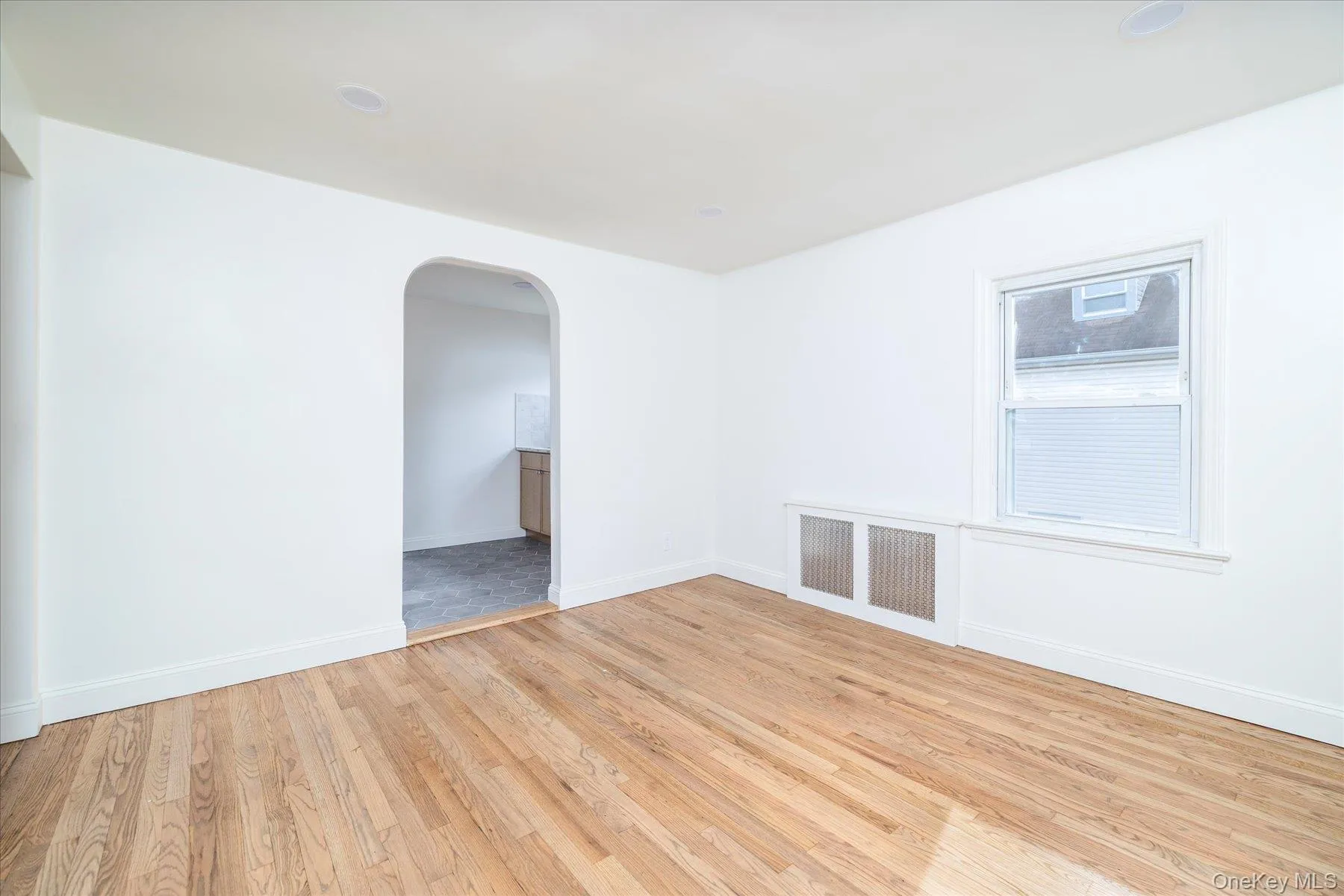 Living room featuring light wood flooring, plenty of natural light, arched entryway Living room featuring light wood flooring, plenty of natural light, arched entryway