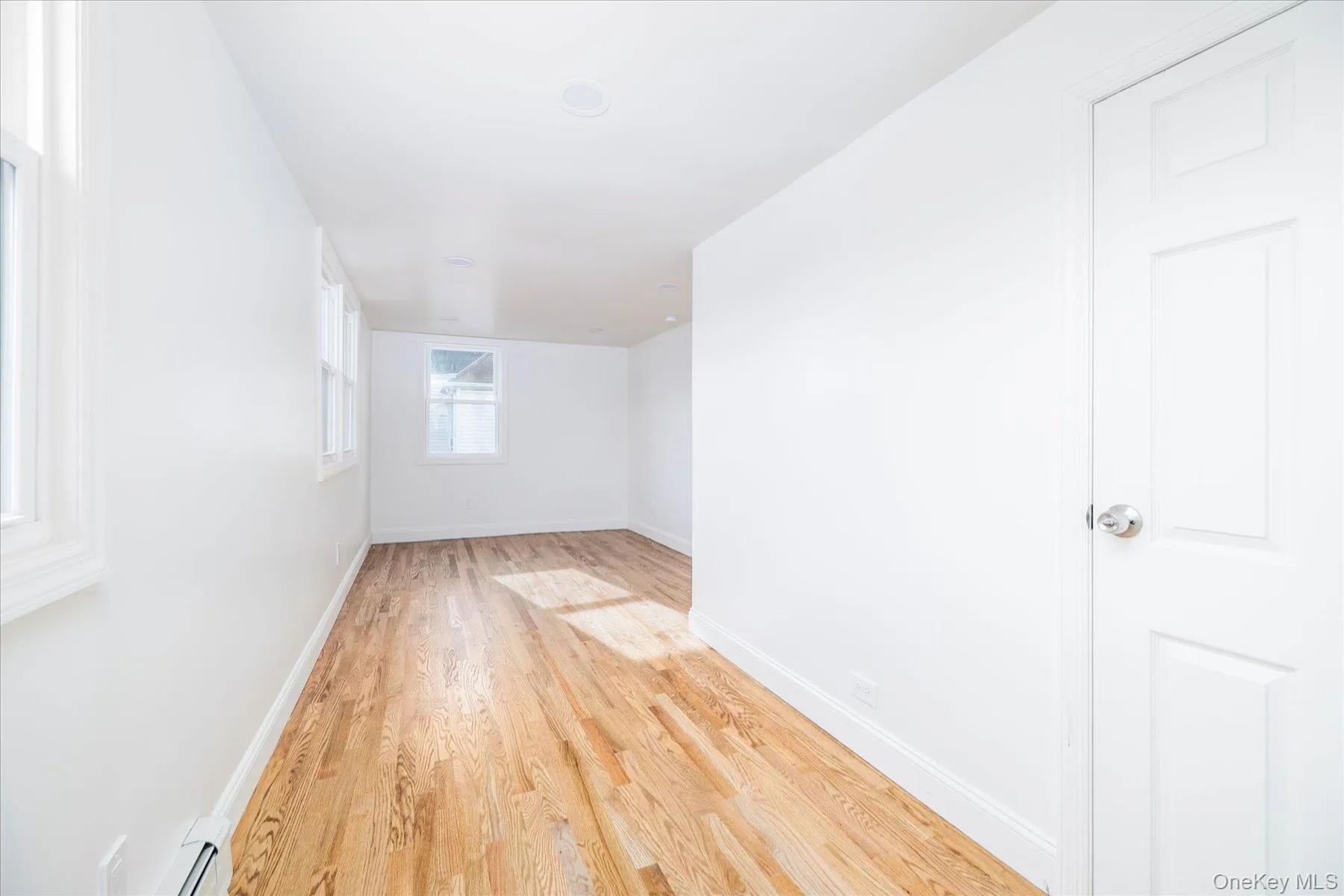 Primary bedroom featuring light wood flooring, plenty of natural light, alcove, 2 closets Primary bedroom featuring light wood flooring, plenty of natural light, alcove, 2 closets