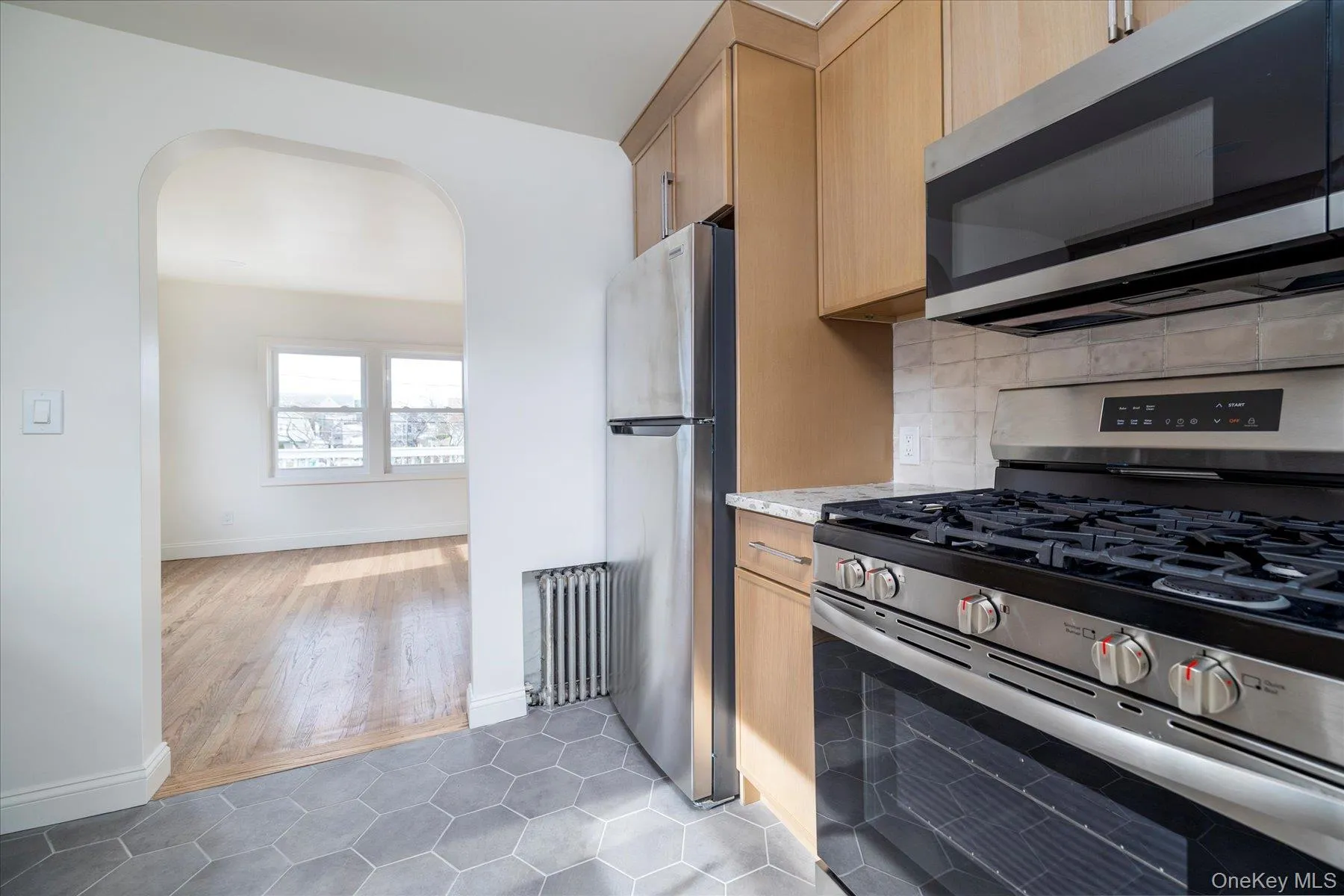 New kitchen featuring white oak cabinets, quartz countertops,ceramic backsplash, stainless steel appliances, & grey tile floor New kitchen featuring white oak cabinets, quartz countertops,ceramic backsplash, stainless steel appliances, & grey tile floor