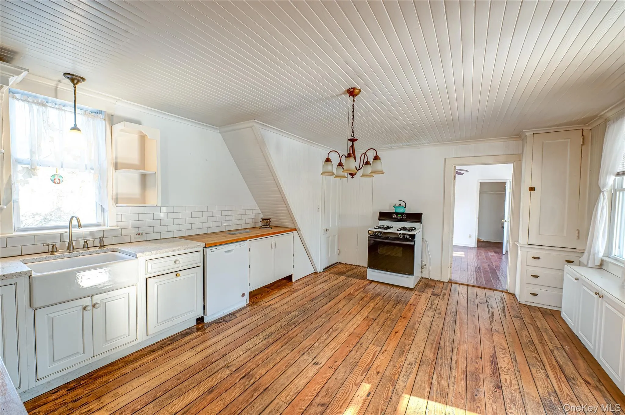 Kitchen featuring white appliances, pendant lighting, light wood-style flooring, white cabinetry, and ornamental molding Kitchen featuring white appliances, pendant lighting, light wood-style flooring, white cabinetry, and ornamental molding