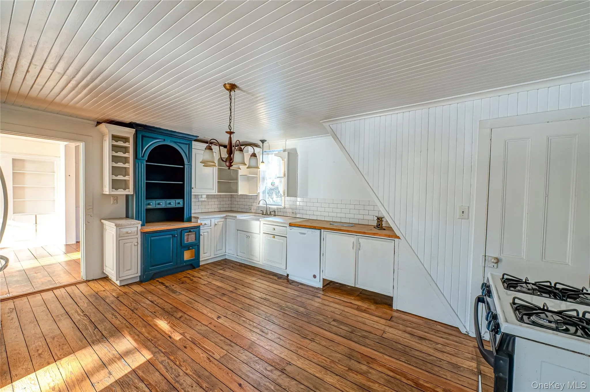 Kitchen with hanging light fixtures, white cabinetry, light wood-type flooring, range with gas stovetop, and dishwasher Kitchen with hanging light fixtures, white cabinetry, light wood-type flooring, range with gas stovetop, and dishwasher