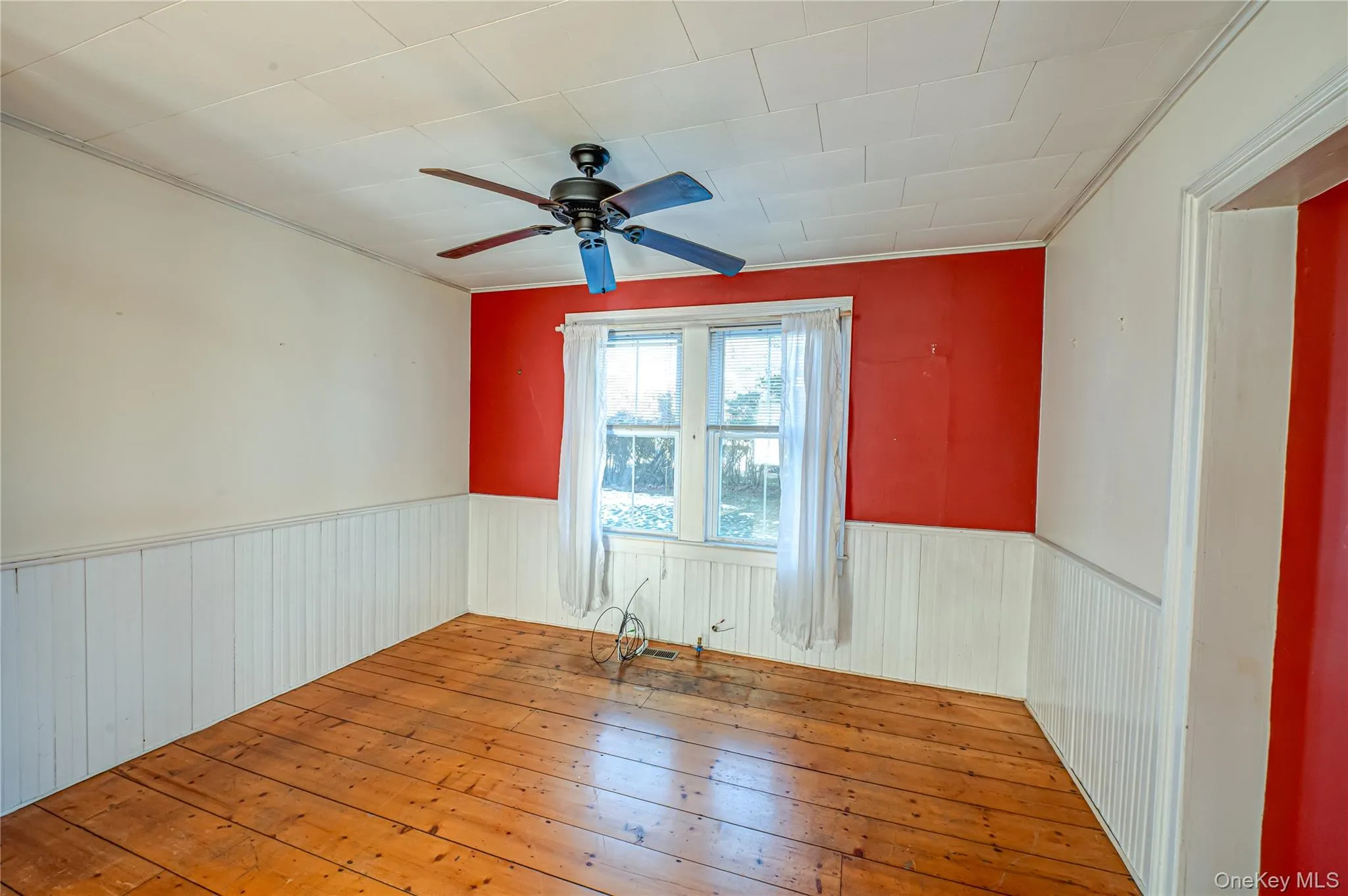 Unfurnished room with hardwood / wood-style floors, ceiling fan, and wainscoting Unfurnished room with hardwood / wood-style floors, ceiling fan, and wainscoting