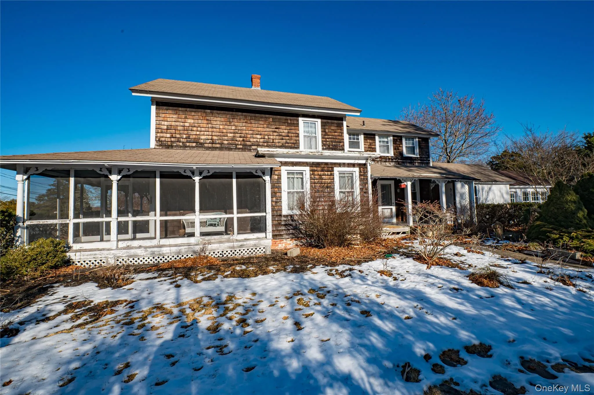 Rear view of house featuring a chimney, roof with shingles, and a sunroom Rear view of house featuring a chimney, roof with shingles, and a sunroom