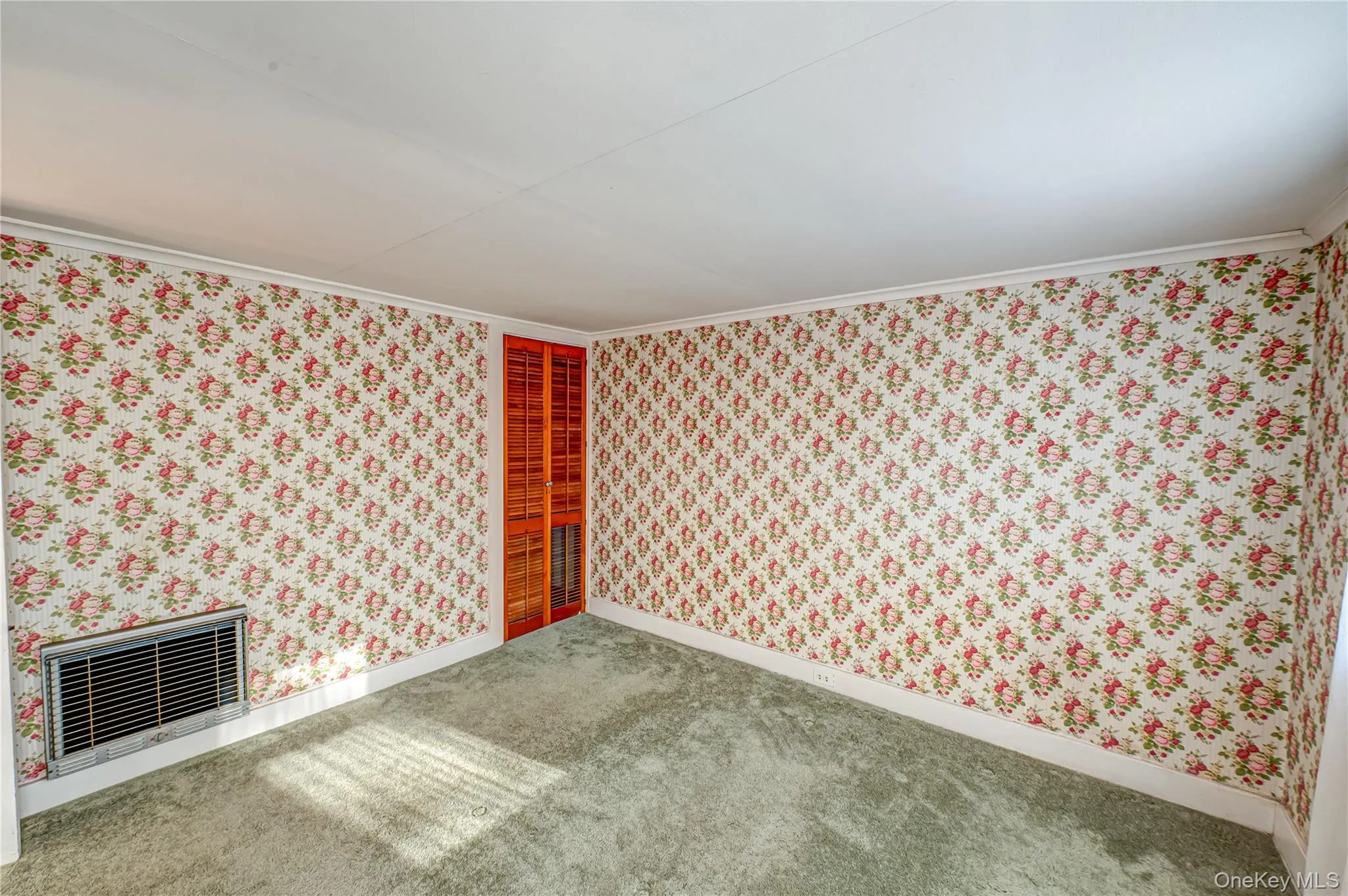 Carpeted empty room with wallpapered walls and heating unit Carpeted empty room with wallpapered walls and heating unit