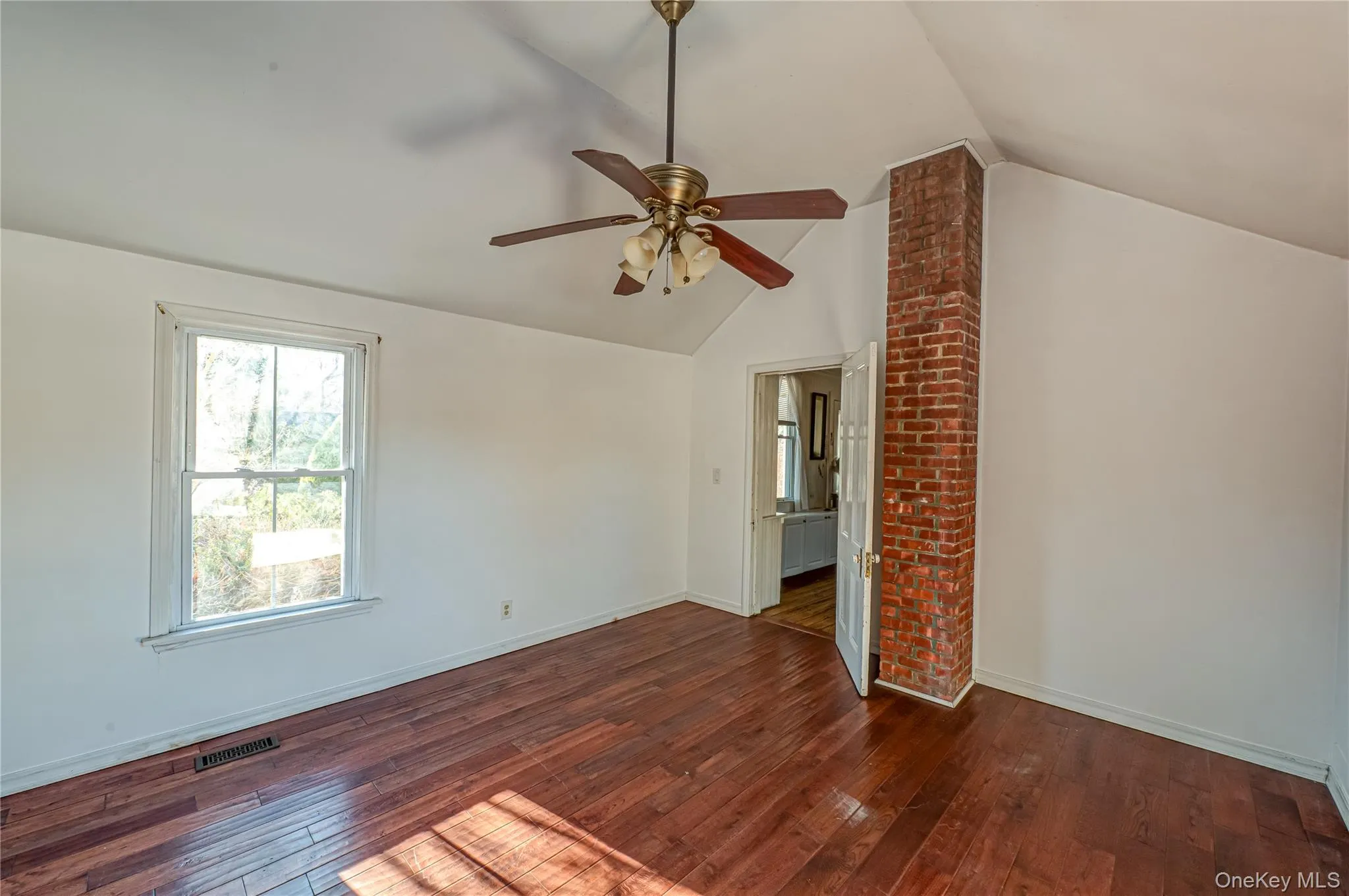 Empty room featuring dark wood-style flooring, healthy amount of natural light, and lofted ceiling Empty room featuring dark wood-style flooring, healthy amount of natural light, and lofted ceiling