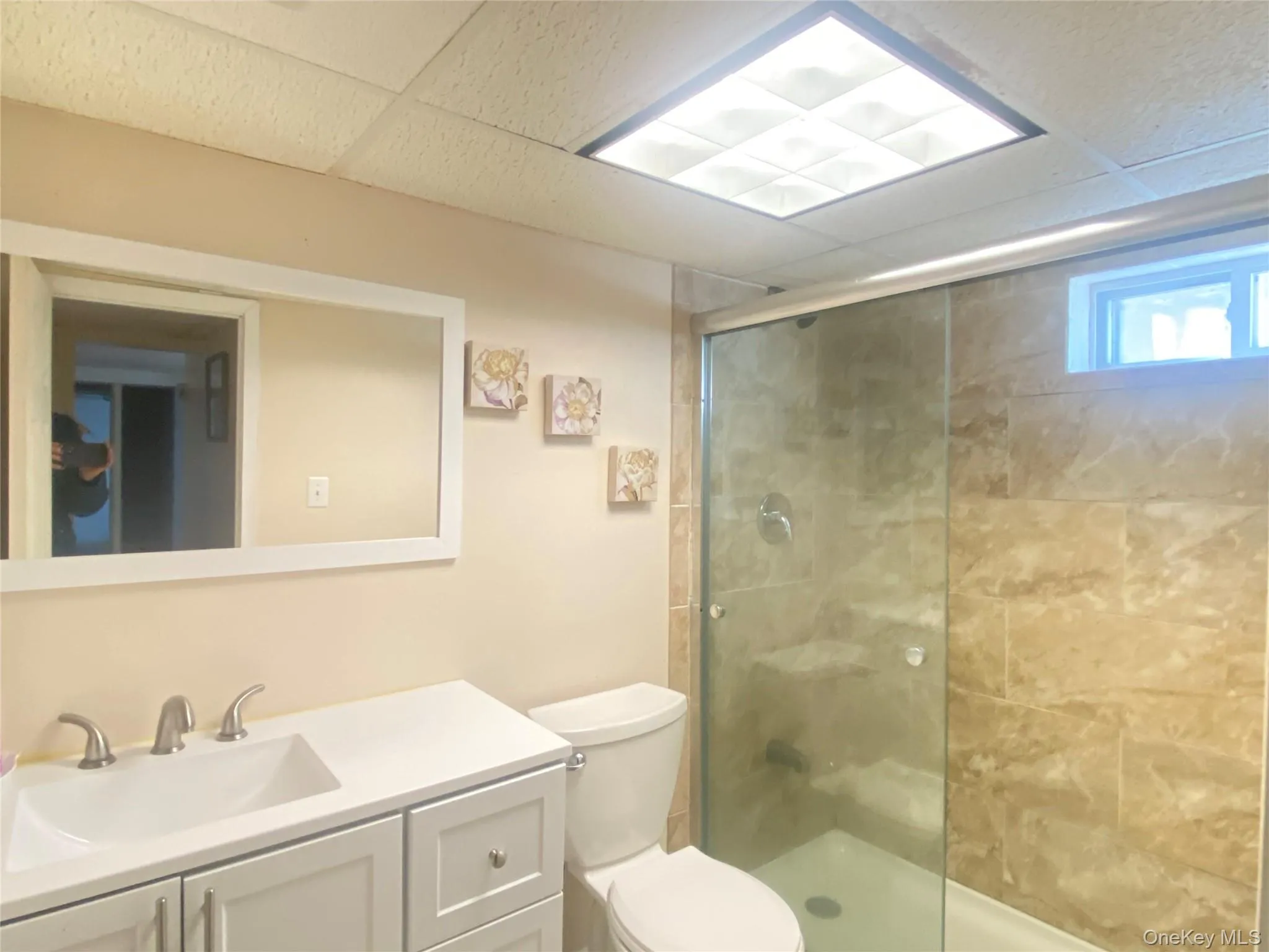 Bathroom featuring a tile shower, vanity, and a drop ceiling Bathroom featuring a tile shower, vanity, and a drop ceiling