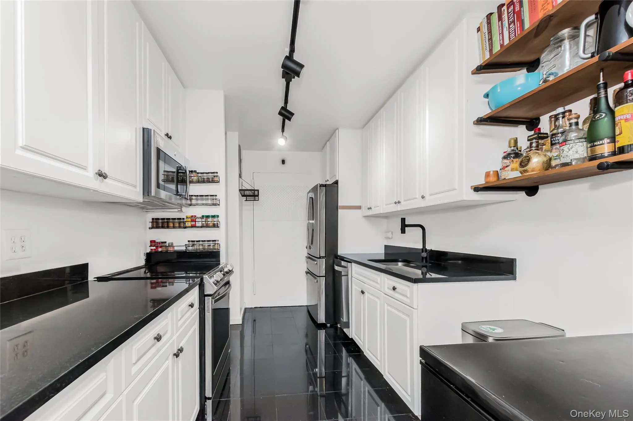 Kitchen with stainless steel appliances, track lighting, white cabinetry, and open shelves Kitchen with stainless steel appliances, track lighting, white cabinetry, and open shelves