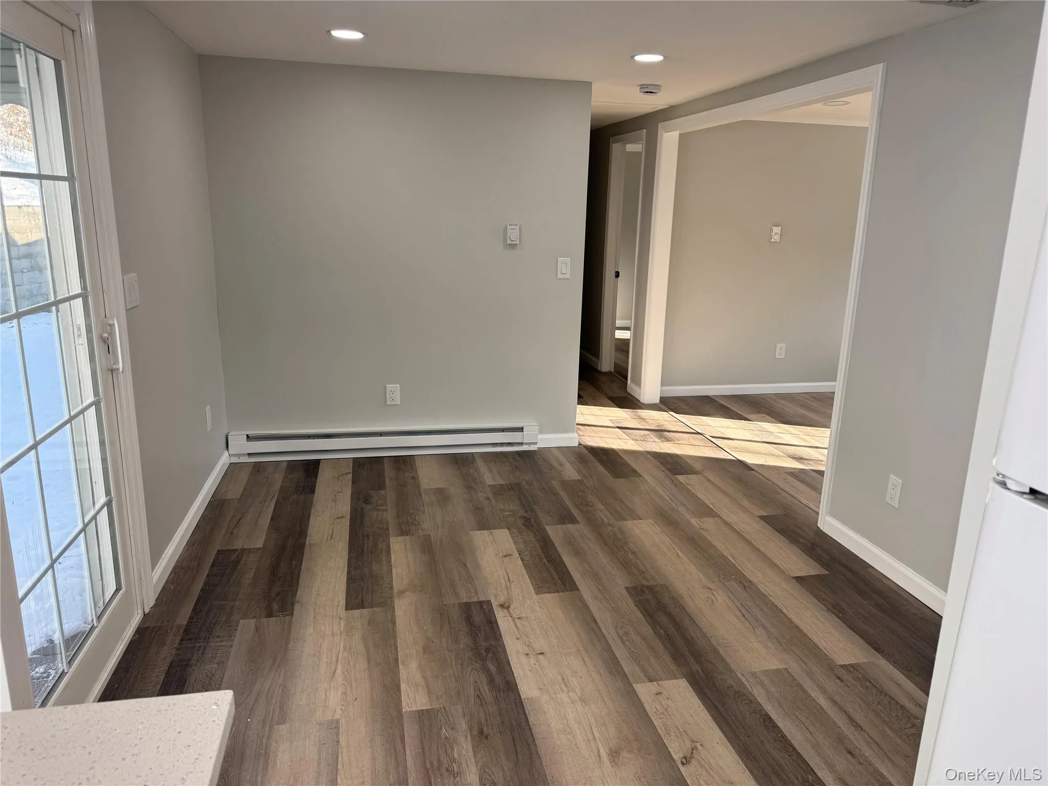 Empty room with dark wood-style flooring, a baseboard heating unit, and recessed lighting Empty room with dark wood-style flooring, a baseboard heating unit, and recessed lighting