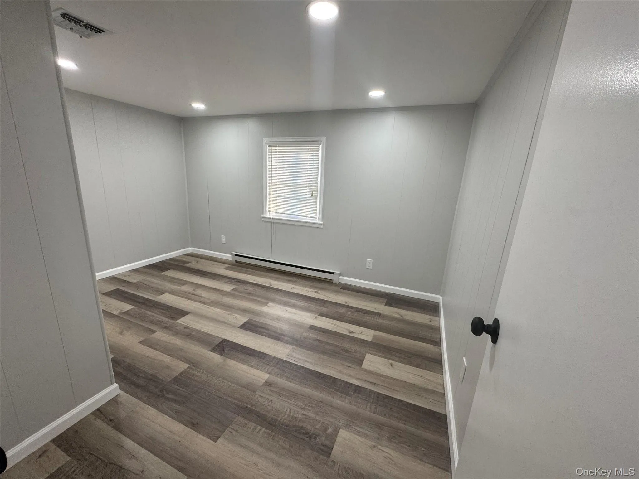 Unfurnished room with light wood-style floors, baseboard heating, and recessed lighting Unfurnished room with light wood-style floors, baseboard heating, and recessed lighting