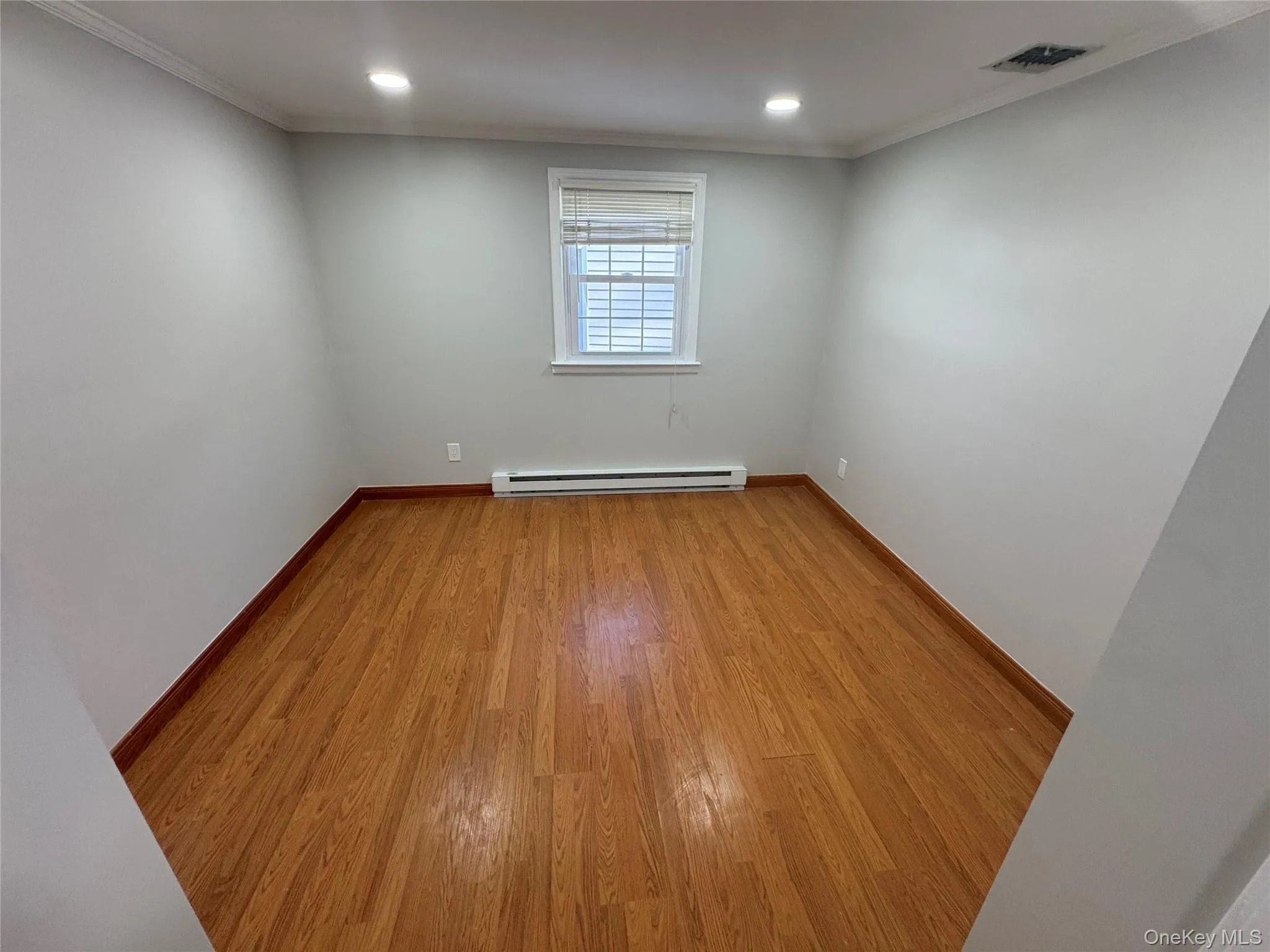 Unfurnished room with light wood-style flooring, ornamental molding, baseboard heating, and recessed lighting Unfurnished room with light wood-style flooring, ornamental molding, baseboard heating, and recessed lighting