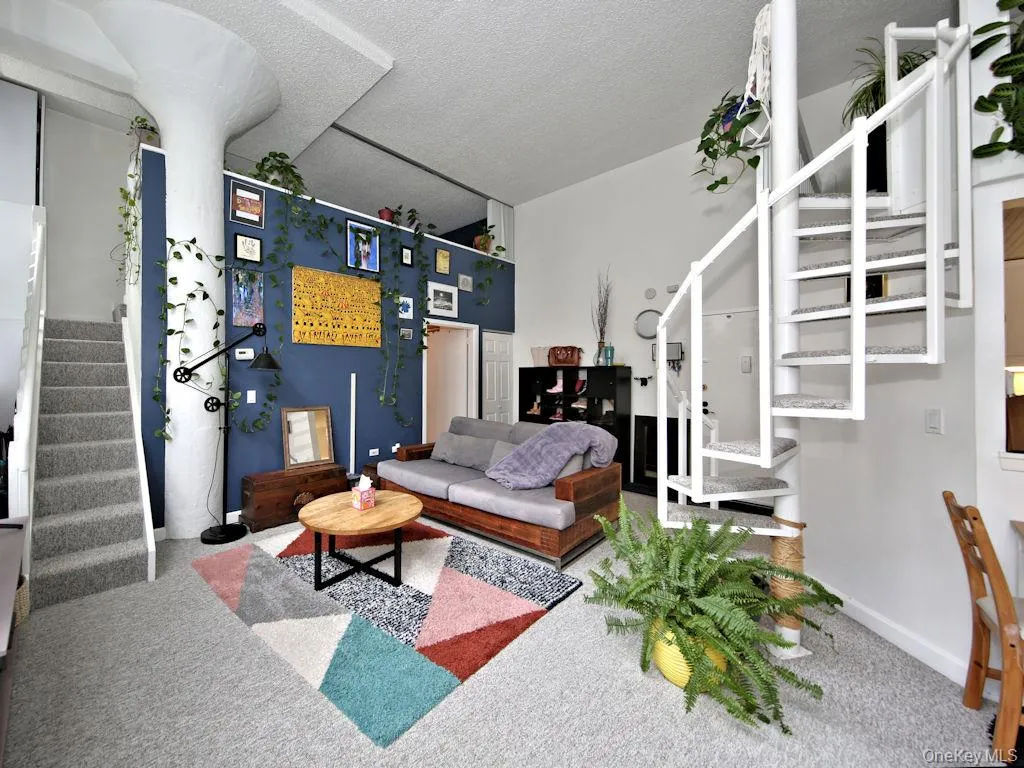 Living area featuring stairs, a towering ceiling, carpet floors, and a textured ceiling Living area featuring stairs, a towering ceiling, carpet floors, and a textured ceiling