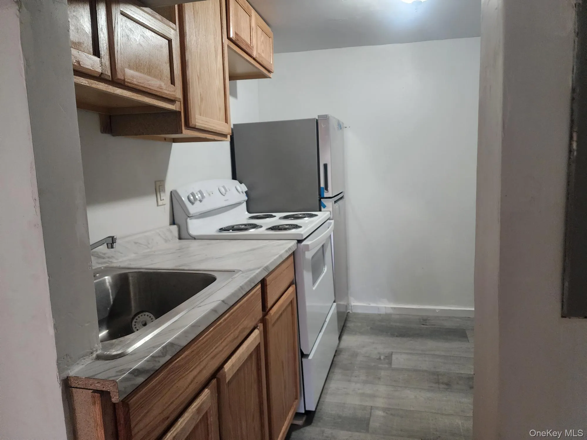 Kitchen with white electric stove, light countertops, brown cabinets, and light wood finished floors Kitchen with white electric stove, light countertops, brown cabinets, and light wood finished floors