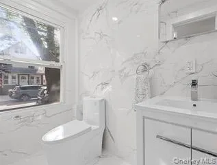 Half bath with stone wall, vanity, and light marble finish floors Half bath with stone wall, vanity, and light marble finish floors