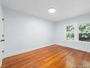 Spare room featuring baseboards and hardwood / wood-style flooring Spare room featuring baseboards and hardwood / wood-style flooring