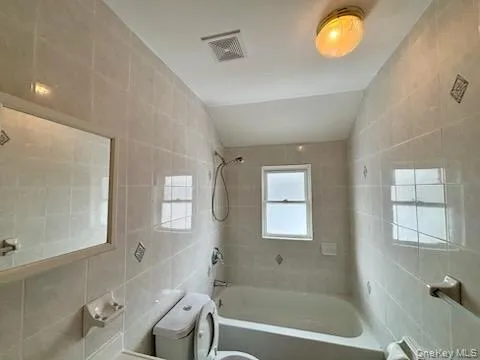 Full bathroom with tile walls and washtub / shower combination Full bathroom with tile walls and washtub / shower combination
