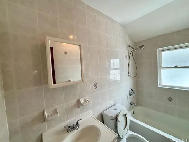 Bathroom with tile walls, shower / bathtub combination, vanity, and lofted ceiling Bathroom with tile walls, shower / bathtub combination, vanity, and lofted ceiling