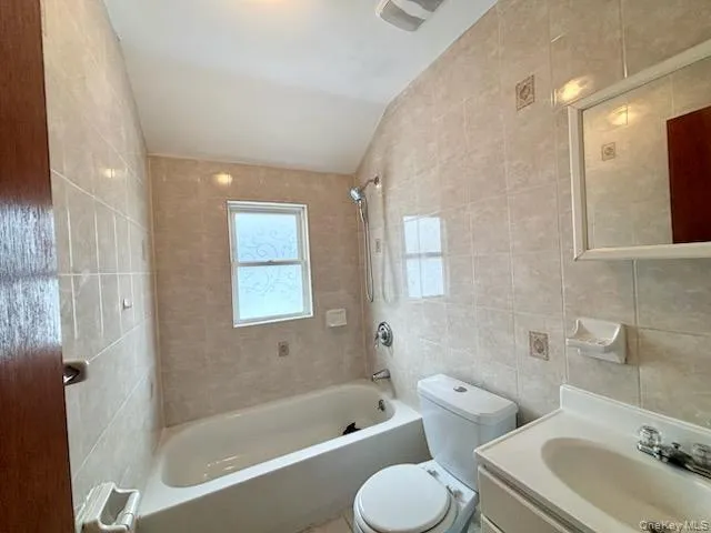 Bathroom with vanity, tile walls, and shower / bathtub combination Bathroom with vanity, tile walls, and shower / bathtub combination