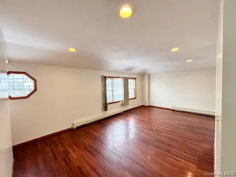 Unfurnished room with a baseboard radiator, dark wood finished floors, and recessed lighting Unfurnished room with a baseboard radiator, dark wood finished floors, and recessed lighting