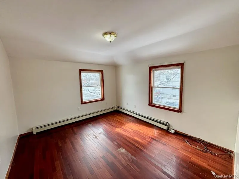 Empty room featuring a baseboard radiator, hardwood / wood-style floors, and lofted ceiling Empty room featuring a baseboard radiator, hardwood / wood-style floors, and lofted ceiling