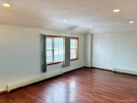 Empty room featuring a baseboard heating unit, recessed lighting, and dark wood finished floors Empty room featuring a baseboard heating unit, recessed lighting, and dark wood finished floors
