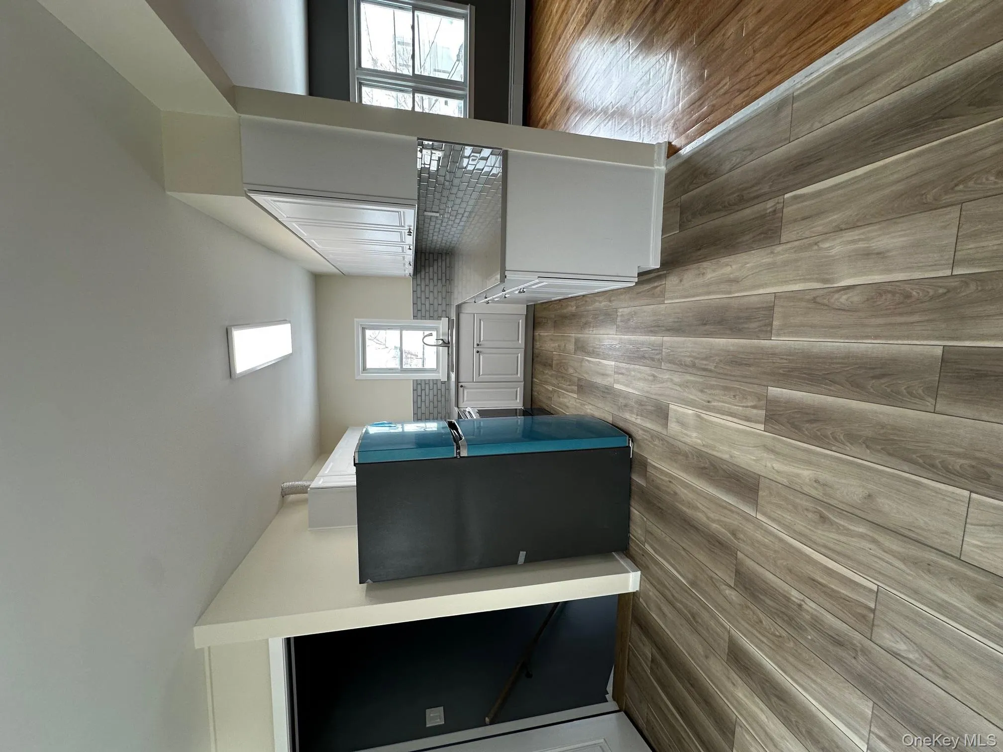 Kitchen featuring refrigerator, white cabinetry, tasteful backsplash, and light wood-type flooring Kitchen featuring refrigerator, white cabinetry, tasteful backsplash, and light wood-type flooring