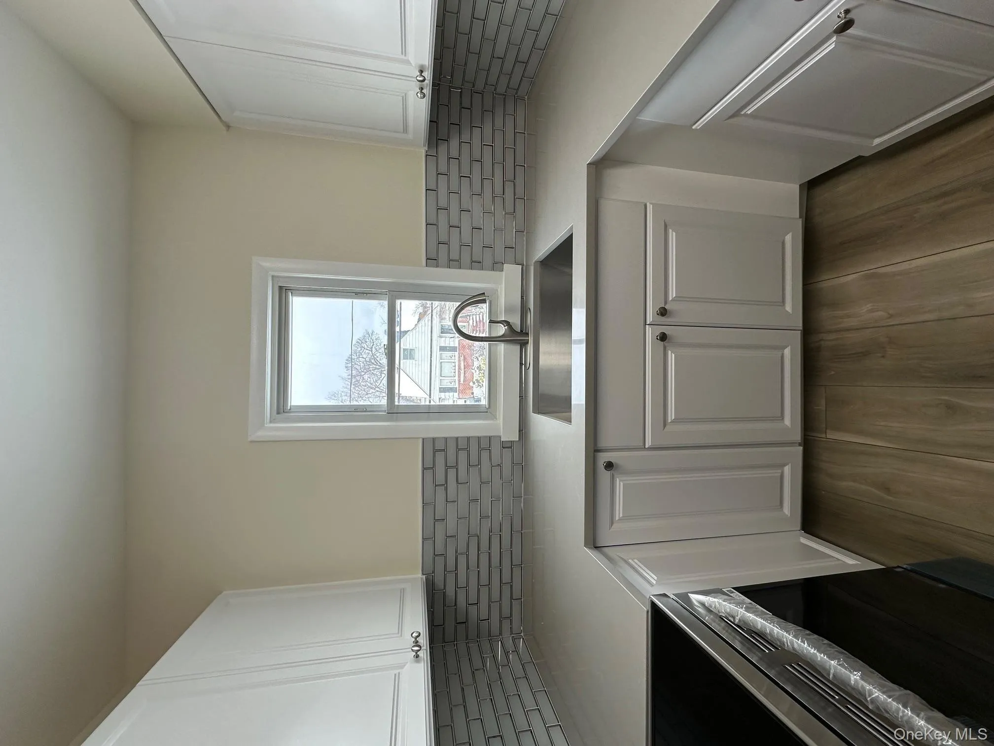 Kitchen featuring white cabinetry, stove, dark wood-style floors, and tasteful backsplash Kitchen featuring white cabinetry, stove, dark wood-style floors, and tasteful backsplash