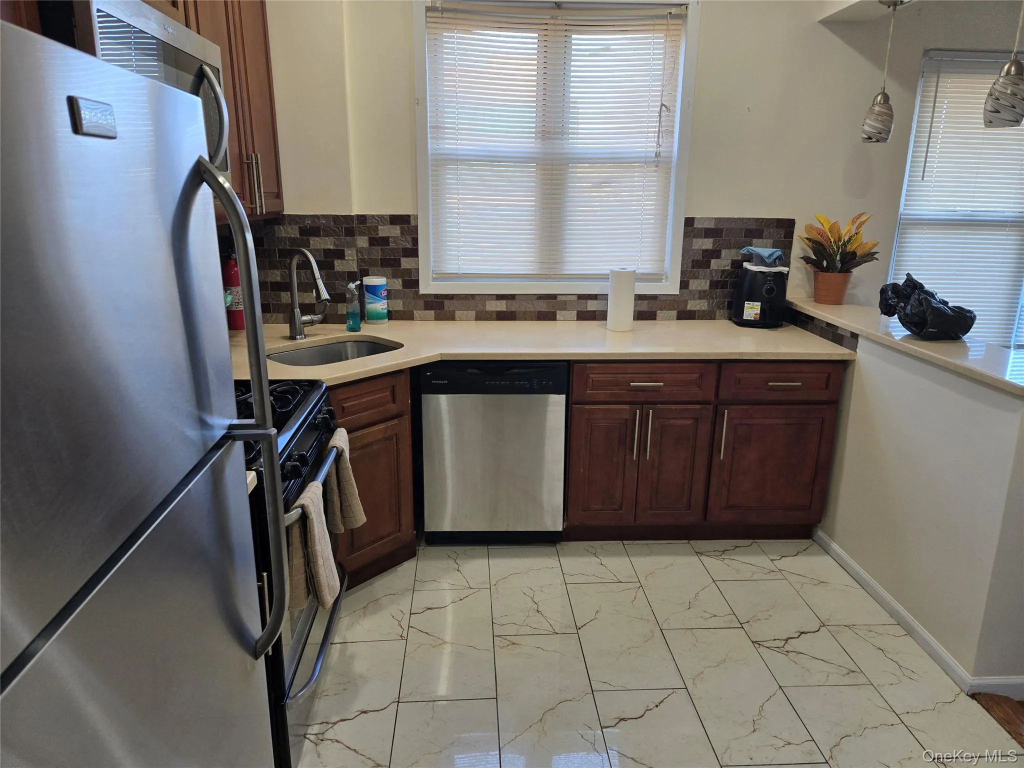 Kitchen with appliances with stainless steel finishes, light finish flooring, tasteful backsplash, and light stone counters Kitchen with appliances with stainless steel finishes, light finish flooring, tasteful backsplash, and light stone counters