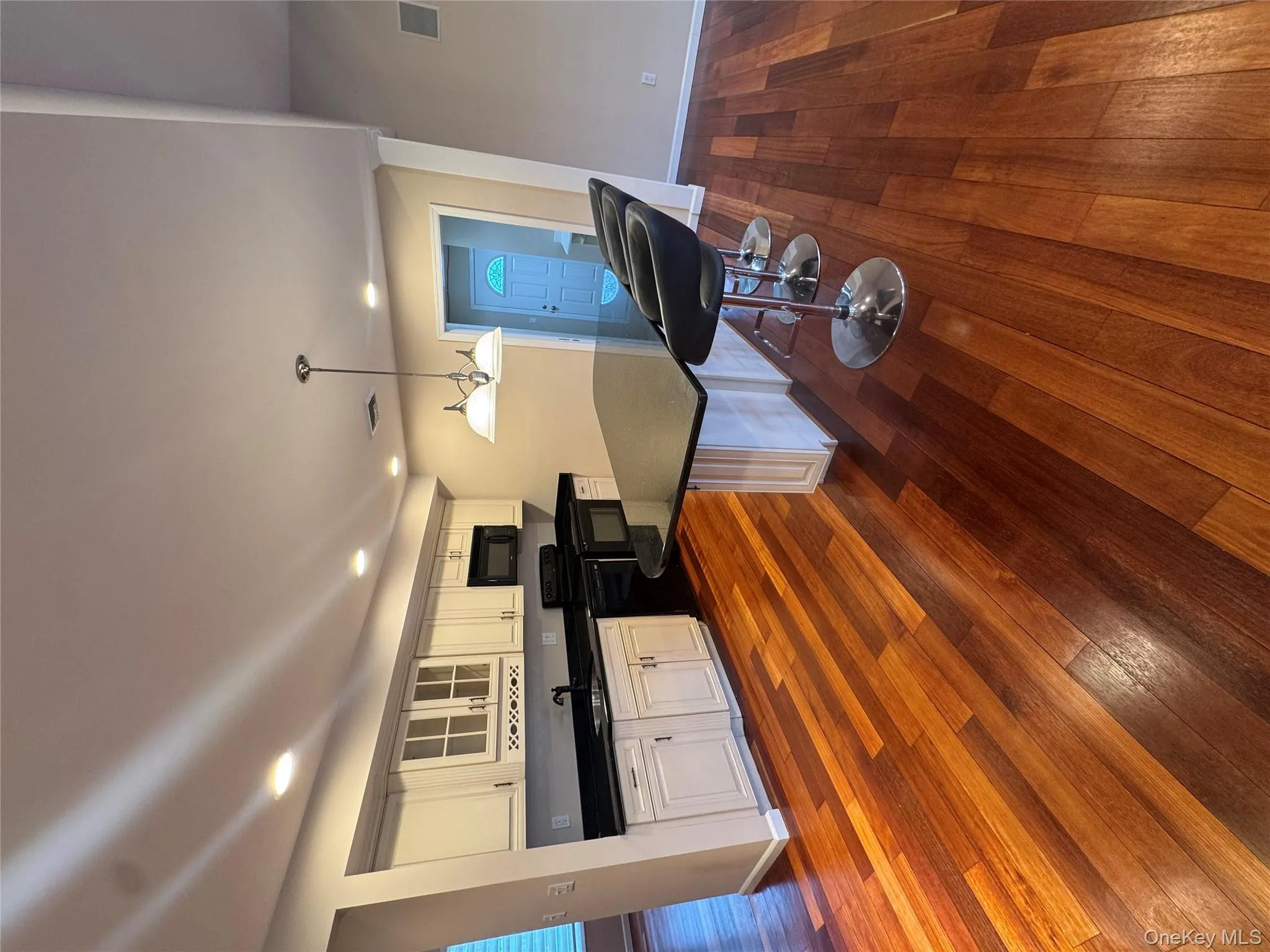 Kitchen with a kitchen bar, glass insert cabinets, hanging light fixtures, dark wood-style flooring, and recessed lighting Kitchen with a kitchen bar, glass insert cabinets, hanging light fixtures, dark wood-style flooring, and recessed lighting