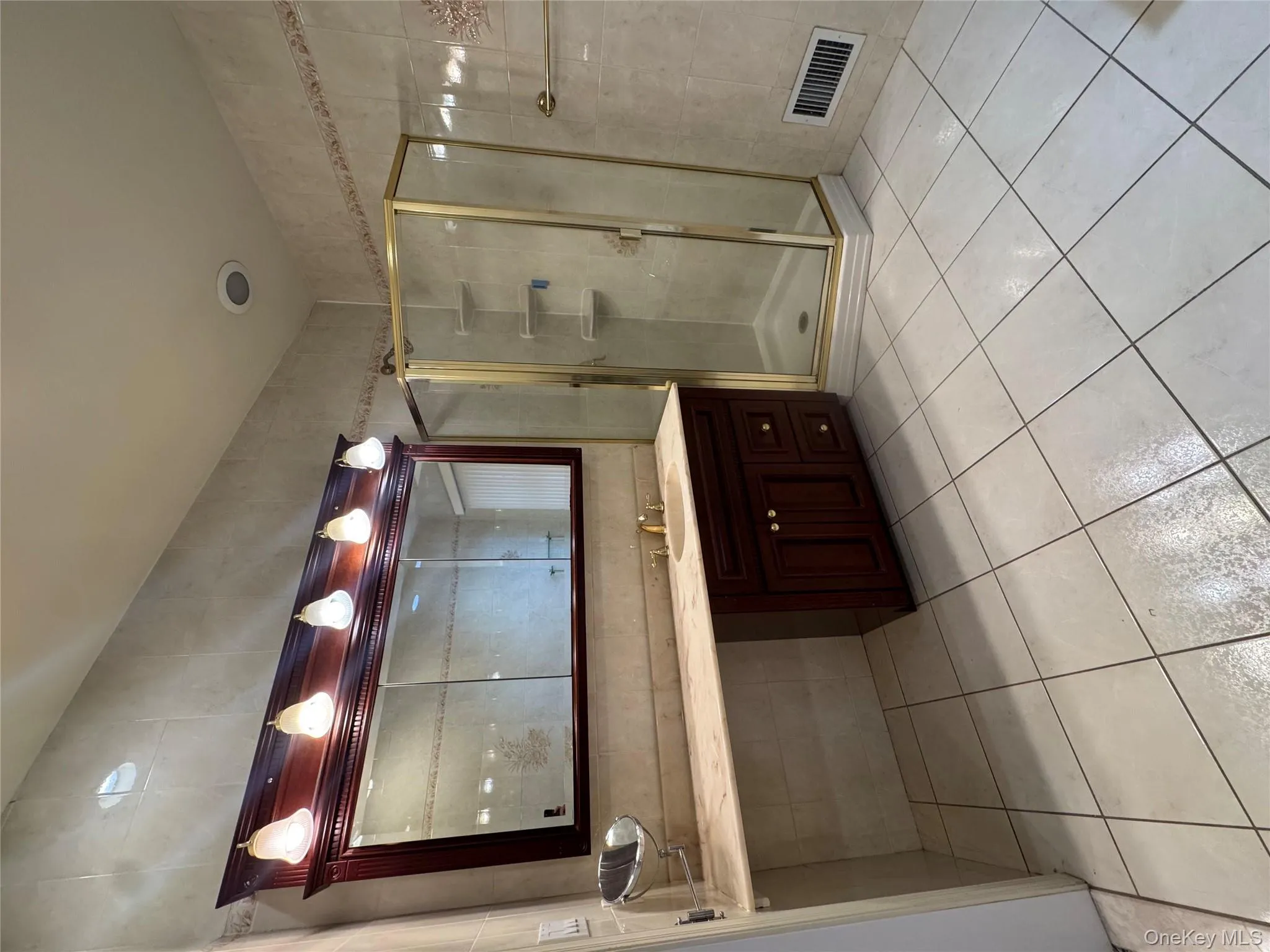 Bathroom with vanity, a shower stall, tile walls, and light tile patterned flooring Bathroom with vanity, a shower stall, tile walls, and light tile patterned flooring