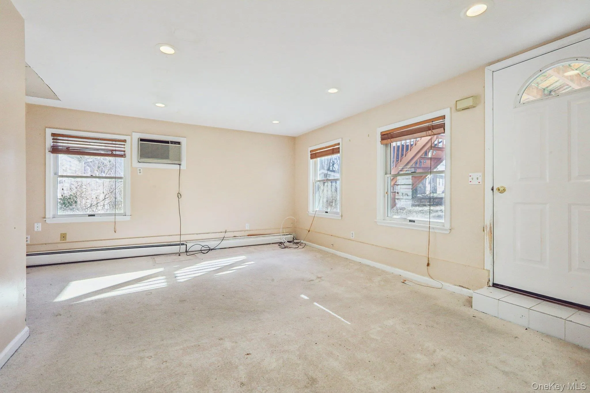 Carpeted foyer featuring a baseboard radiator, recessed lighting, and an AC wall unit Carpeted foyer featuring a baseboard radiator, recessed lighting, and an AC wall unit