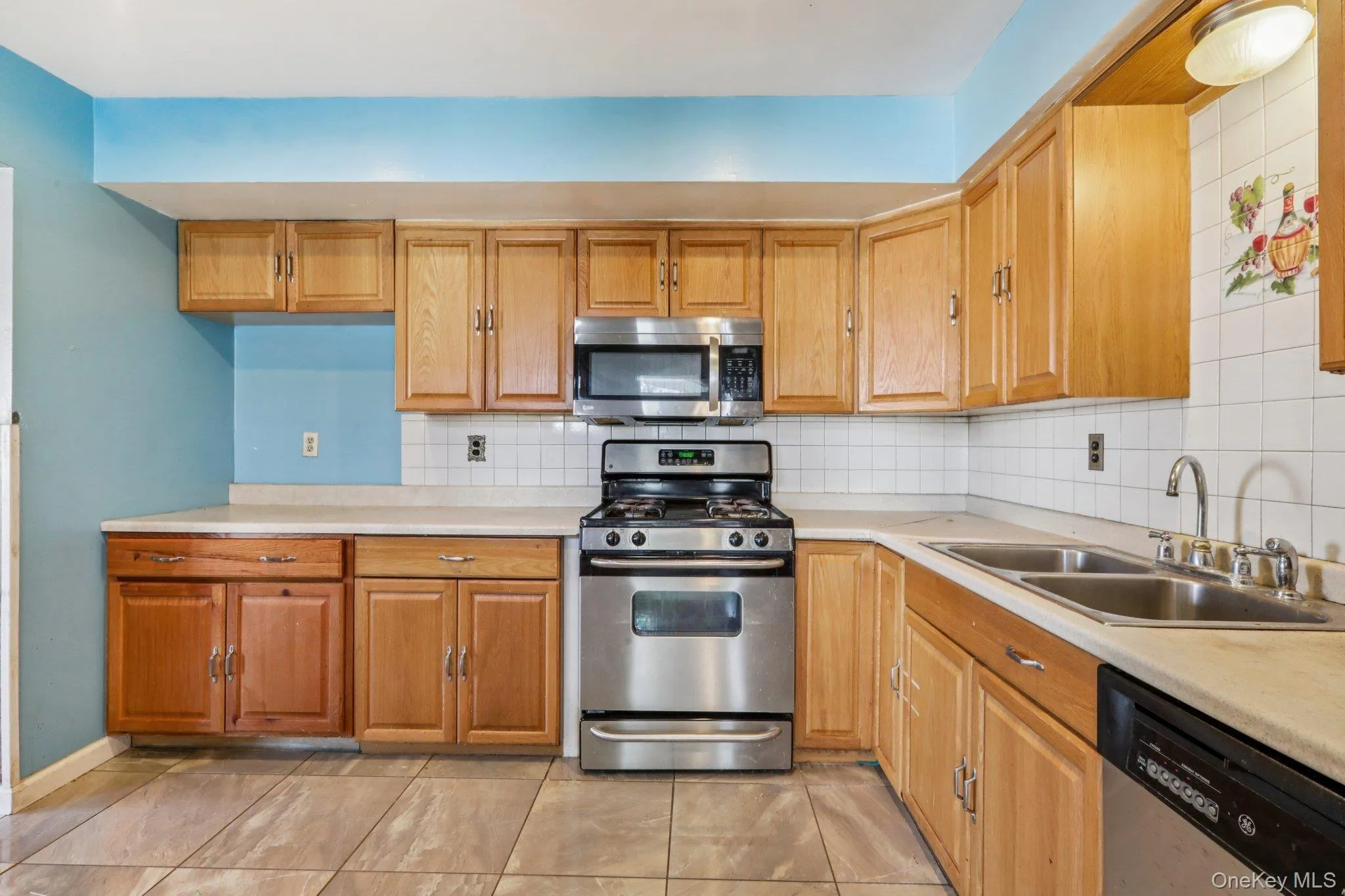 Kitchen featuring stainless steel appliances, light countertops, tasteful backsplash, and brown cabinets Kitchen featuring stainless steel appliances, light countertops, tasteful backsplash, and brown cabinets