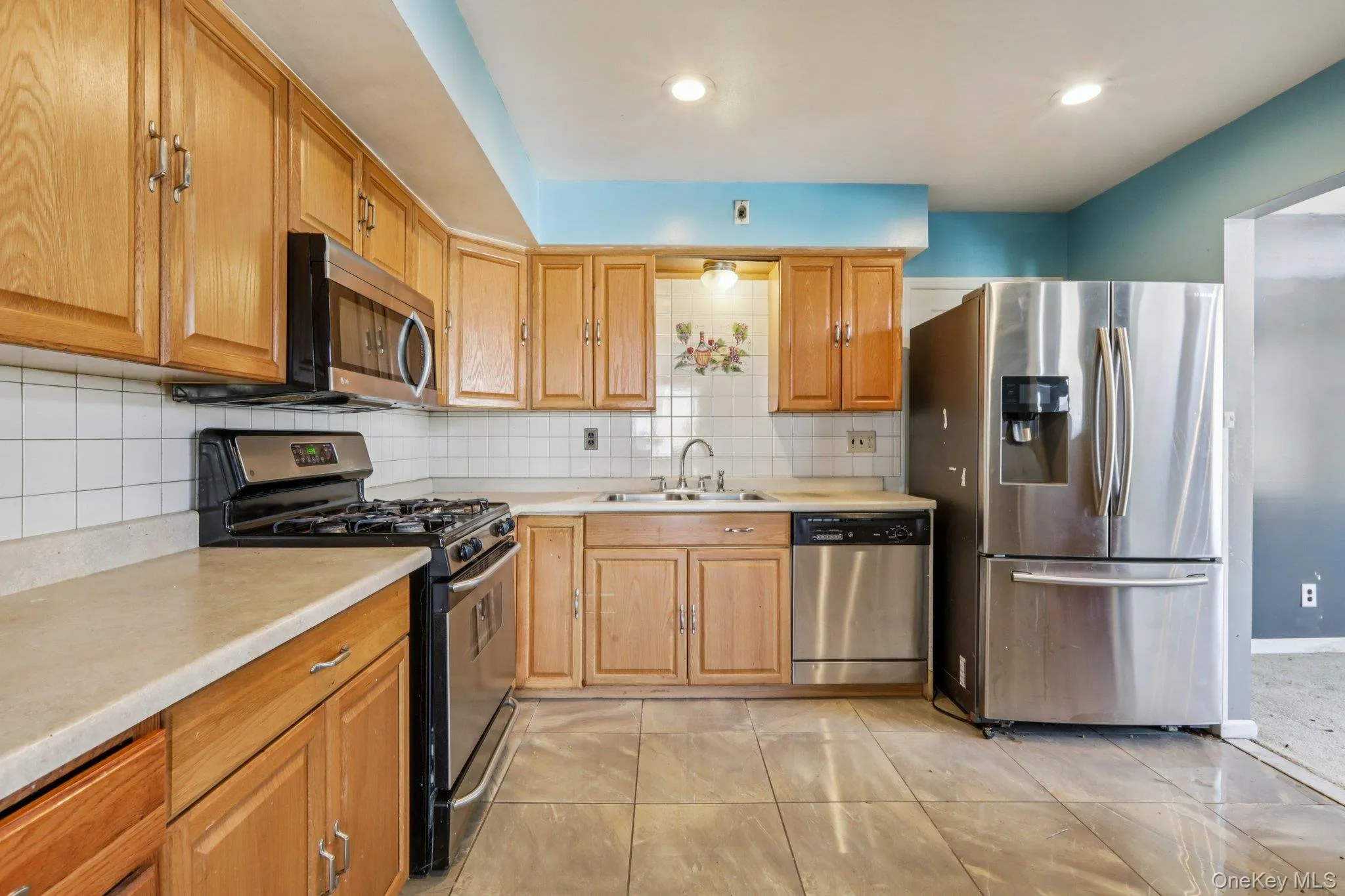 Kitchen with appliances with stainless steel finishes, light countertops, and tasteful backsplash Kitchen with appliances with stainless steel finishes, light countertops, and tasteful backsplash