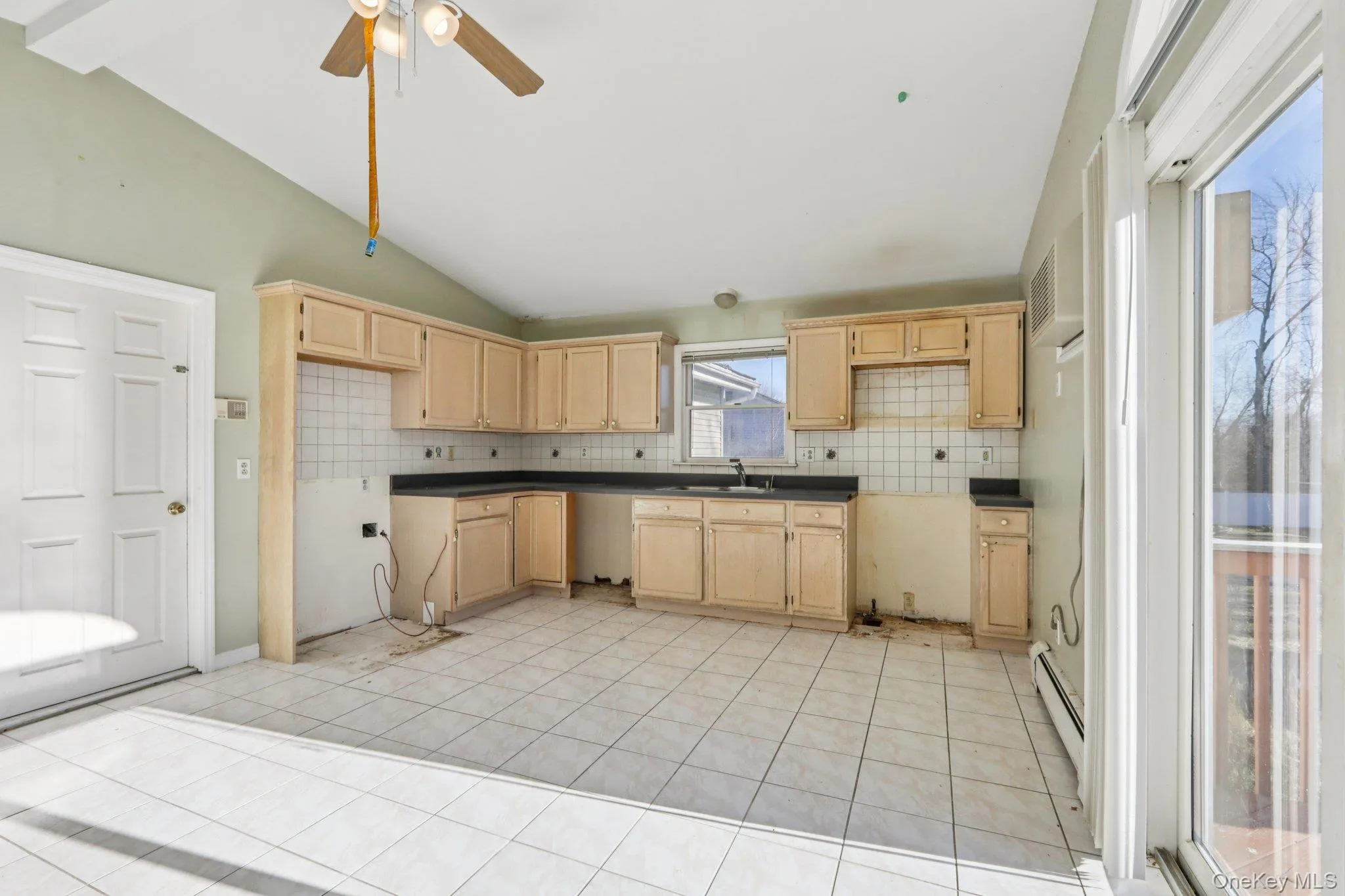 Kitchen with light brown cabinetry, dark countertops, backsplash, beam ceiling, and high vaulted ceiling Kitchen with light brown cabinetry, dark countertops, backsplash, beam ceiling, and high vaulted ceiling