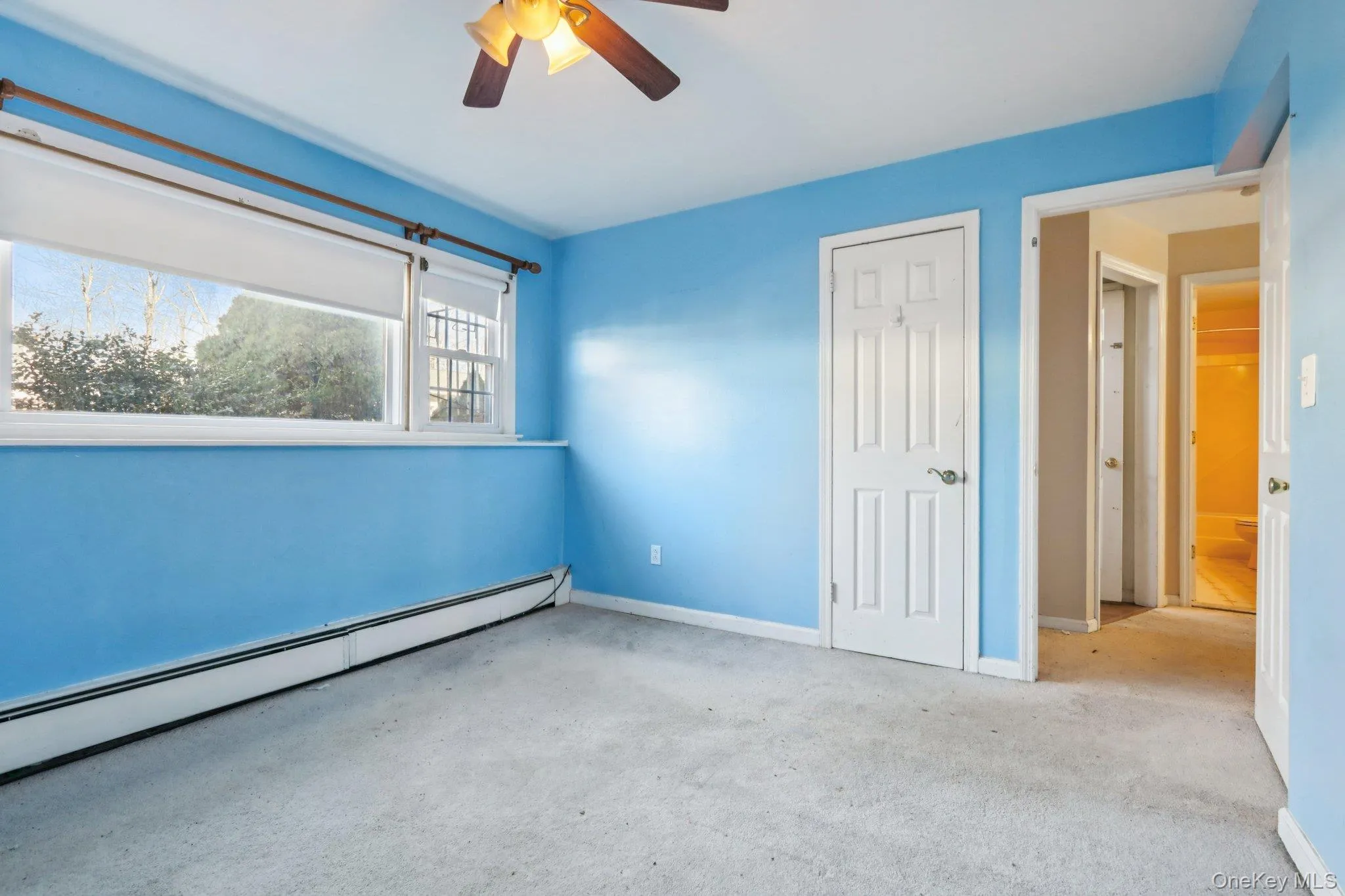 Unfurnished bedroom with a baseboard radiator, carpet, ceiling fan, and a closet Unfurnished bedroom with a baseboard radiator, carpet, ceiling fan, and a closet
