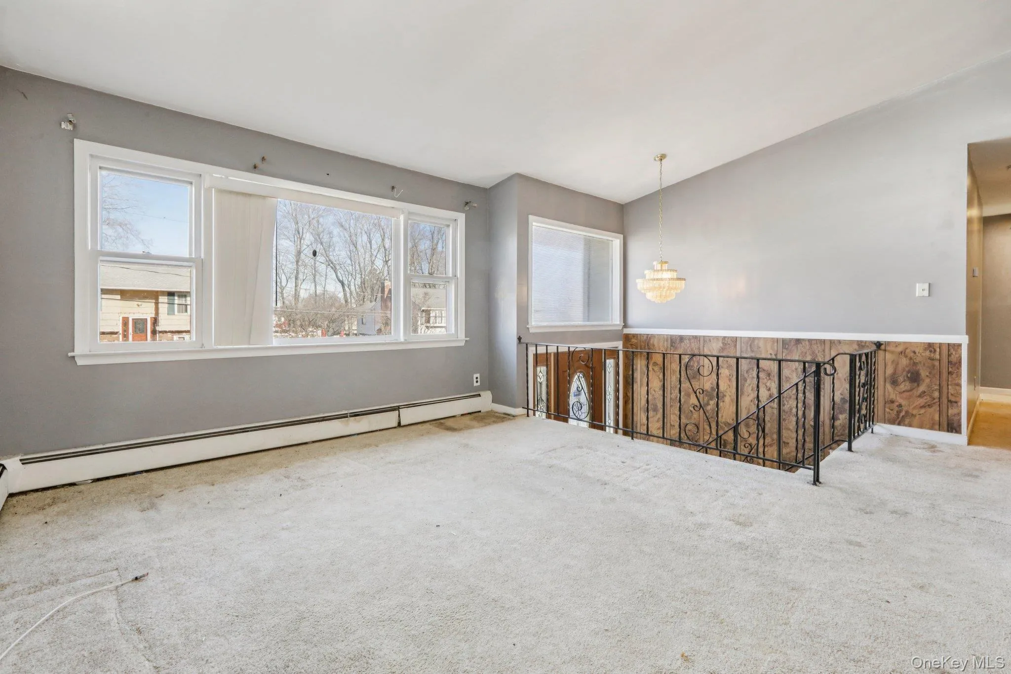 Carpeted spare room featuring baseboard heating, plenty of natural light, and a chandelier Carpeted spare room featuring baseboard heating, plenty of natural light, and a chandelier