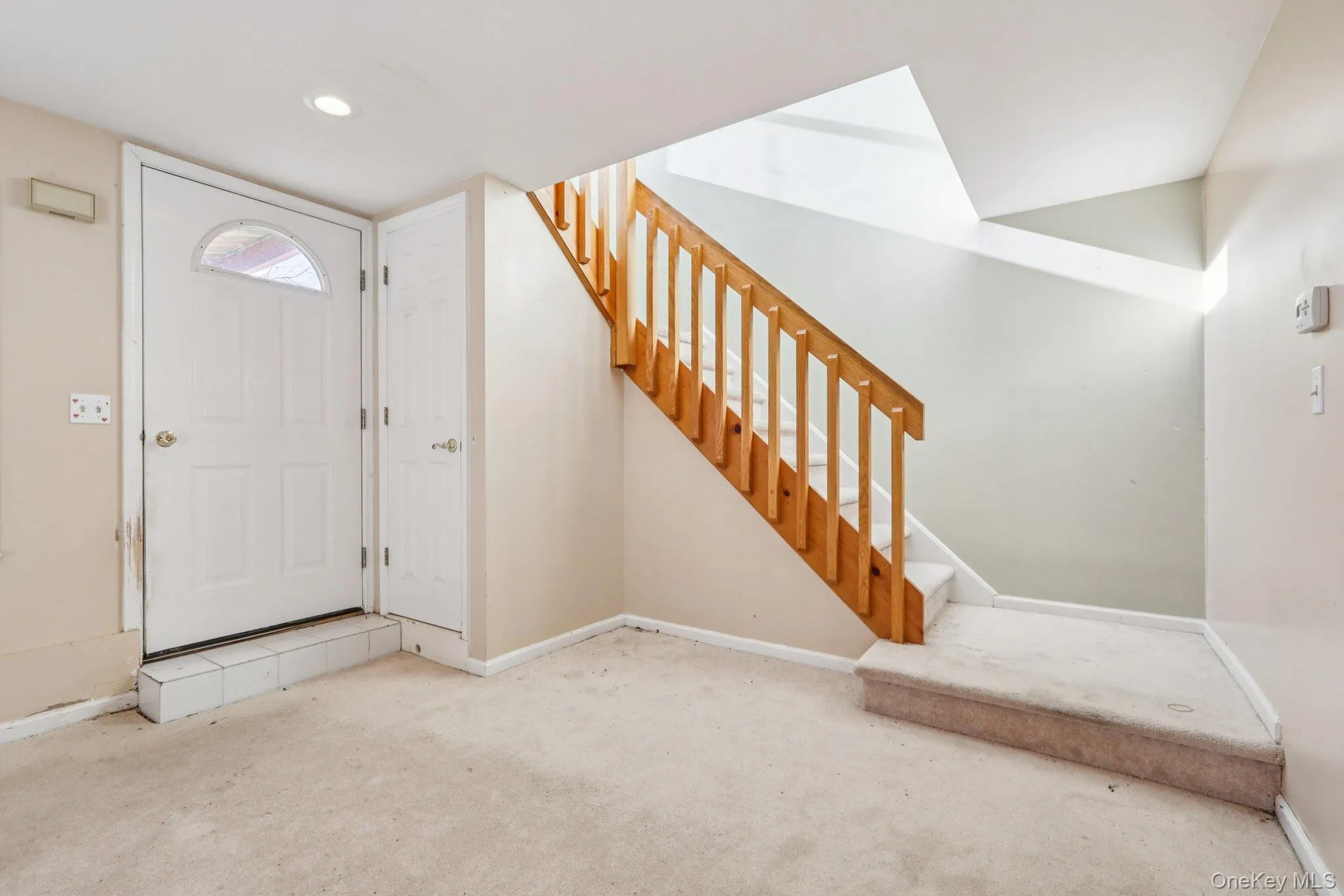 Carpeted foyer featuring baseboards and stairs Carpeted foyer featuring baseboards and stairs