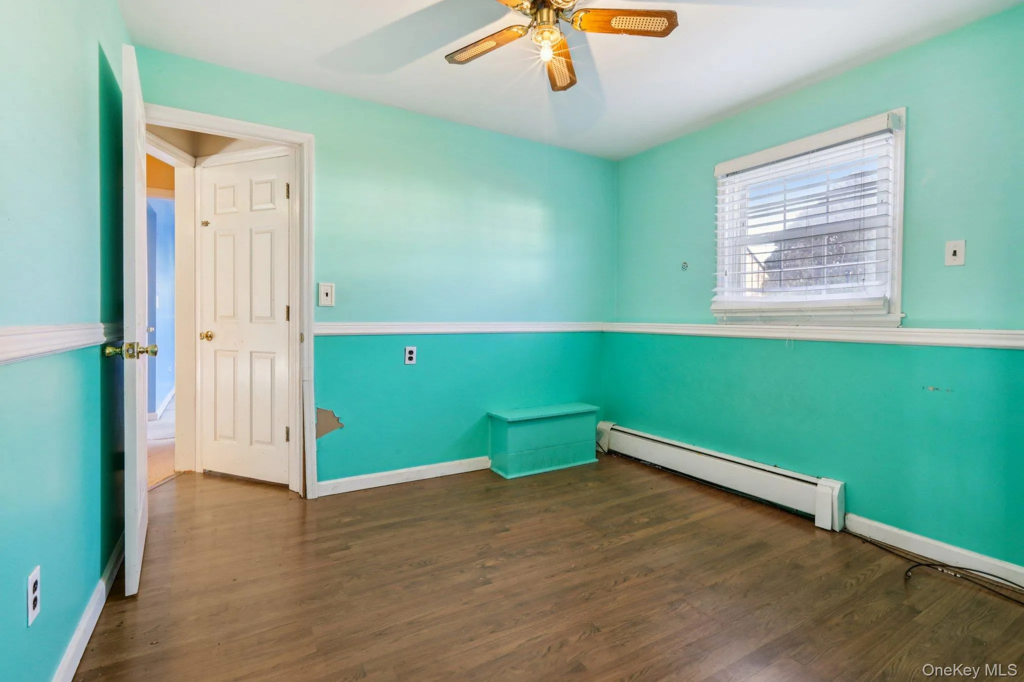 Spare room with a baseboard radiator, dark wood finished floors, and ceiling fan Spare room with a baseboard radiator, dark wood finished floors, and ceiling fan