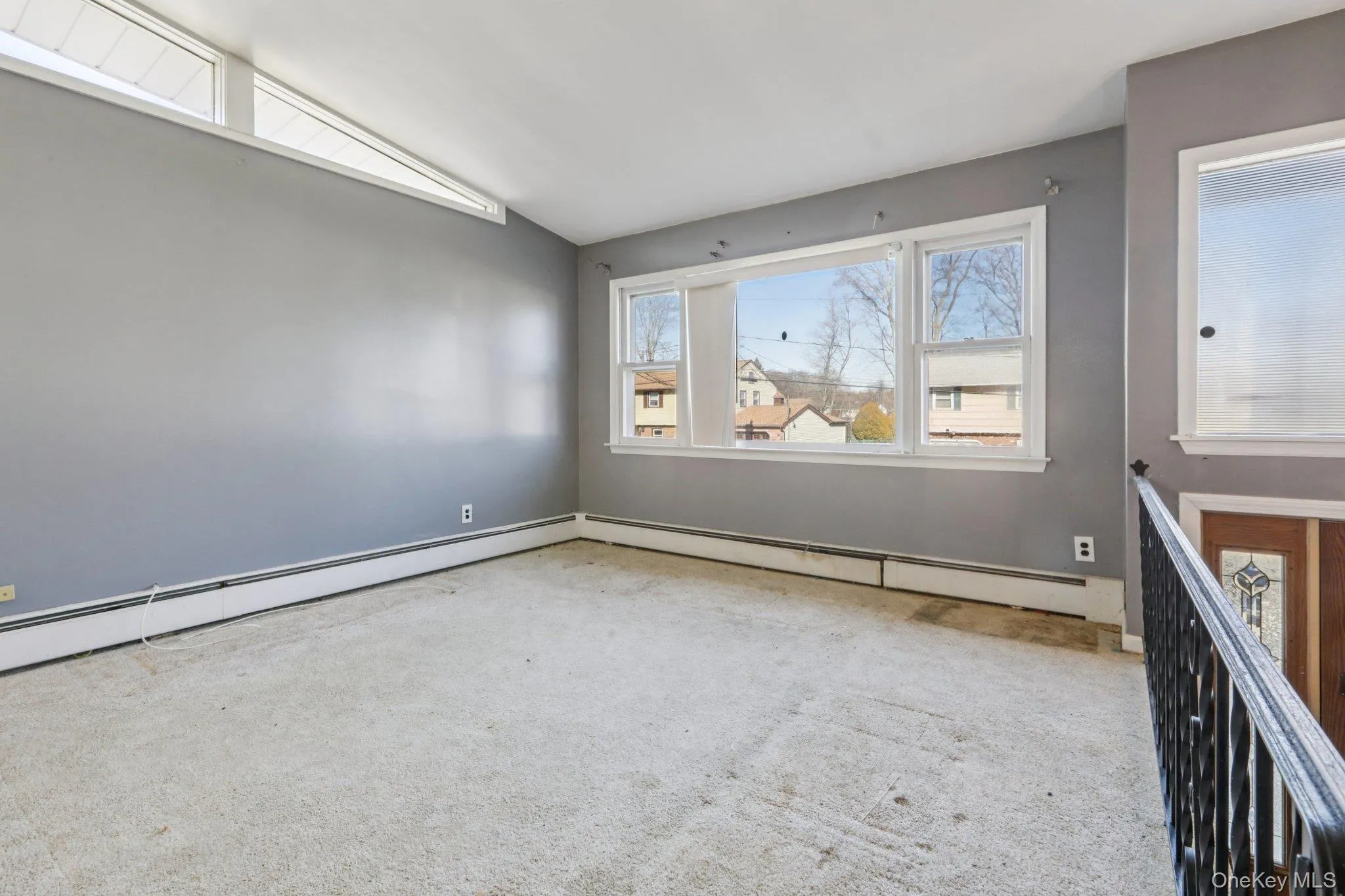 Empty room featuring carpet flooring, lofted ceiling, and a baseboard radiator Empty room featuring carpet flooring, lofted ceiling, and a baseboard radiator