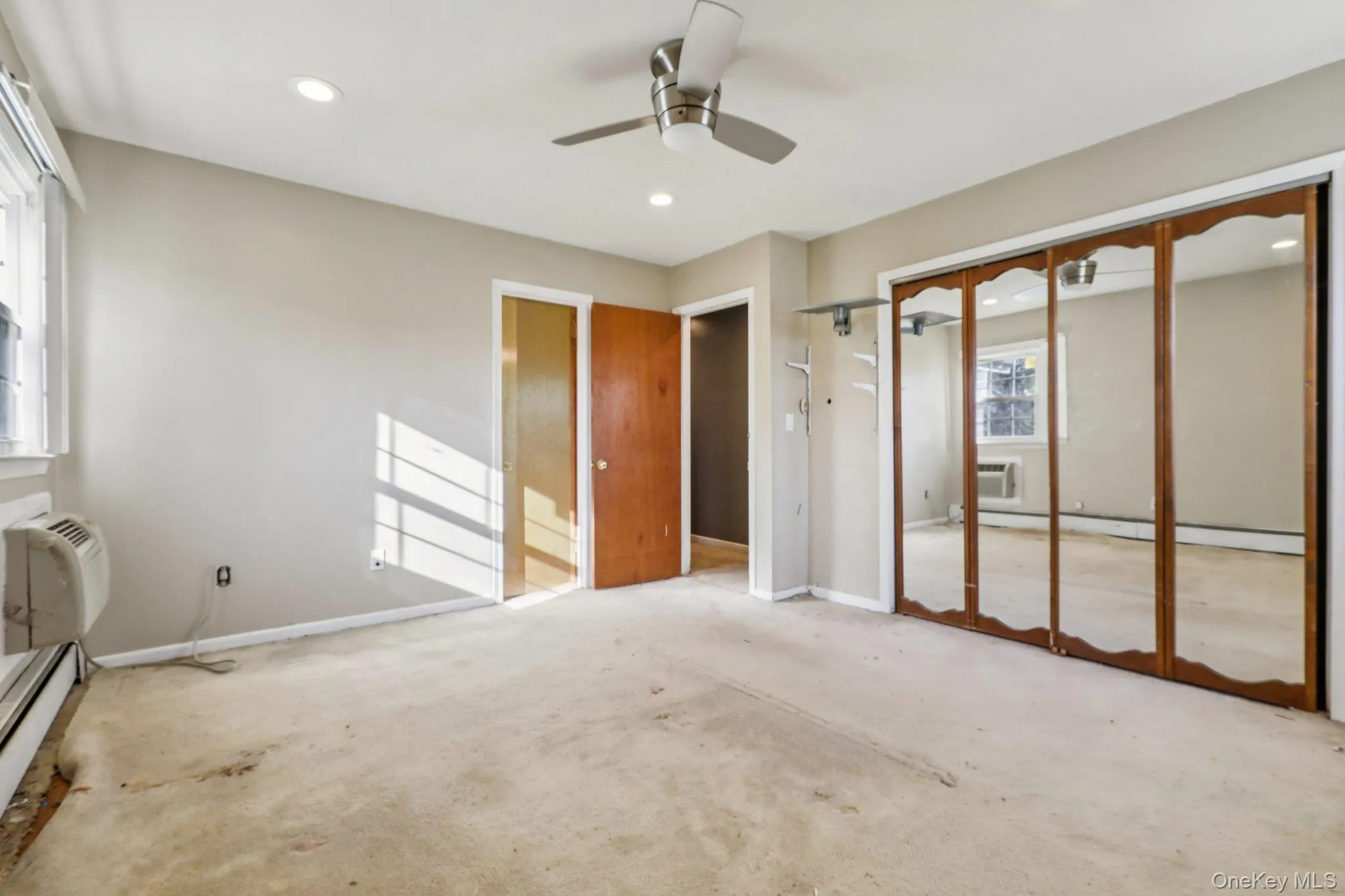Unfurnished bedroom featuring a baseboard radiator, ceiling fan, a closet, recessed lighting, and a wall mounted AC Unfurnished bedroom featuring a baseboard radiator, ceiling fan, a closet, recessed lighting, and a wall mounted AC