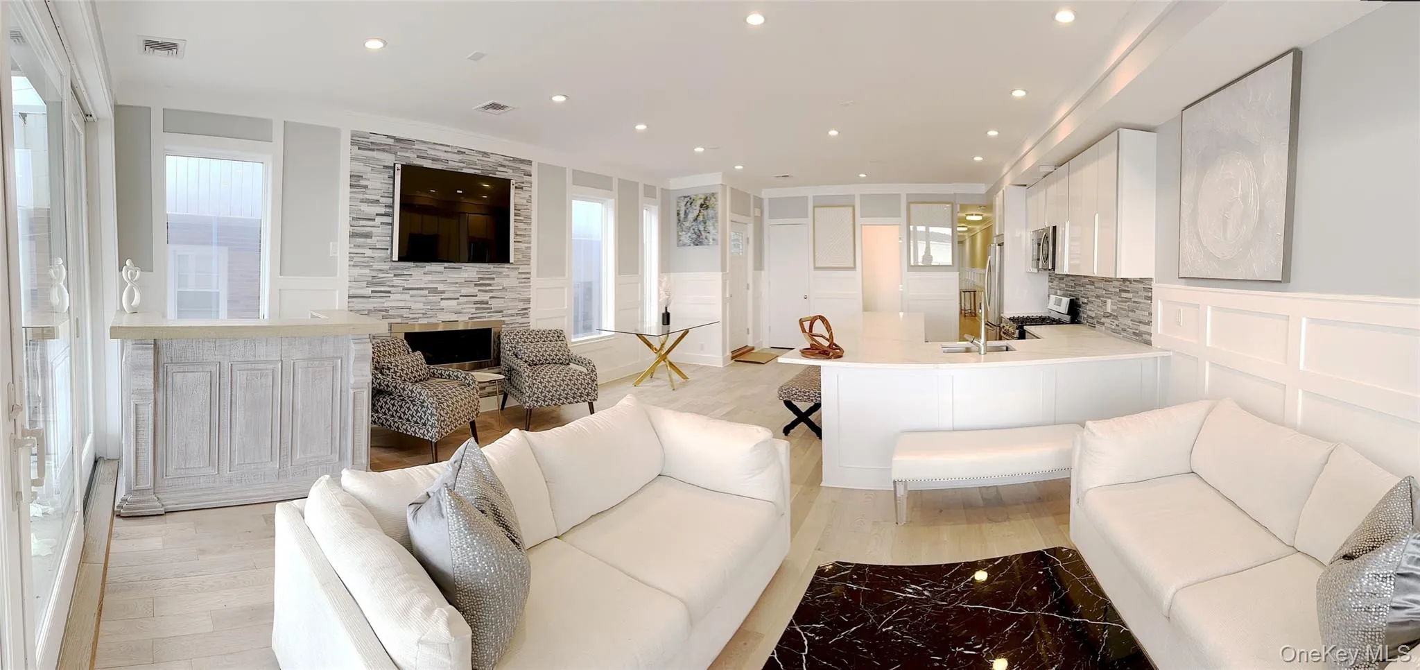 Living room with a decorative wall, wainscoting, light wood finished floors, plenty of natural light, and recessed lighting Living room with a decorative wall, wainscoting, light wood finished floors, plenty of natural light, and recessed lighting