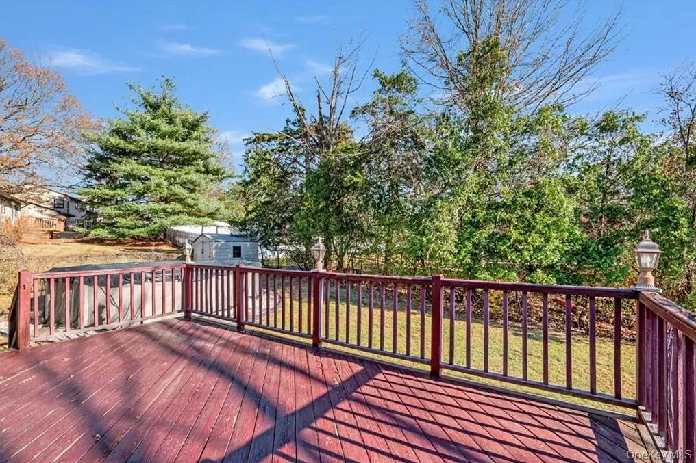 Wooden terrace featuring an outdoor structure and a yard Wooden terrace featuring an outdoor structure and a yard